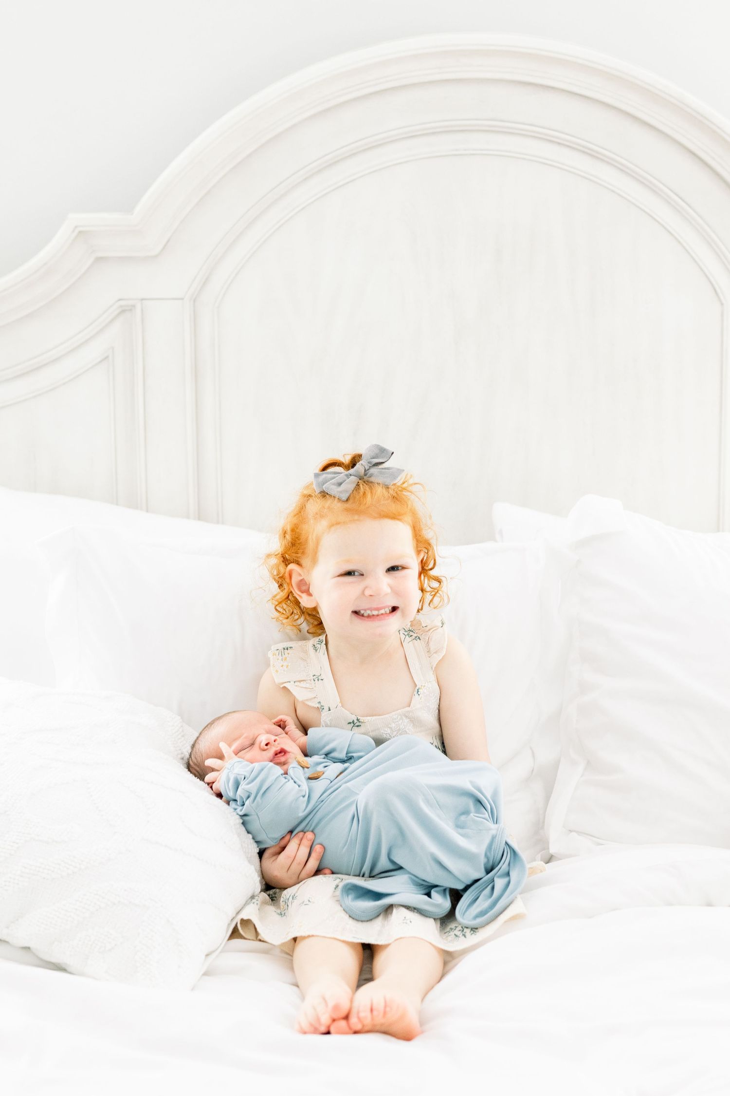Sibling holding newborn baby brother during in-home session in Augusta, GA.