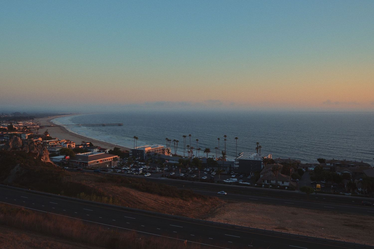 Aerial view of a coastal town at sunset with buildings dotting the shoreline.