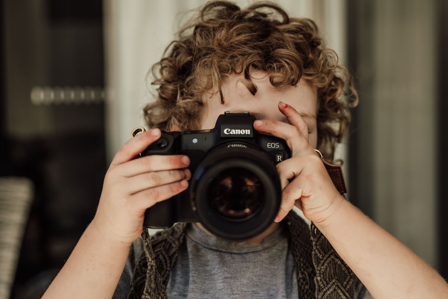 Young photographer holding professional Canon DSLR camera.