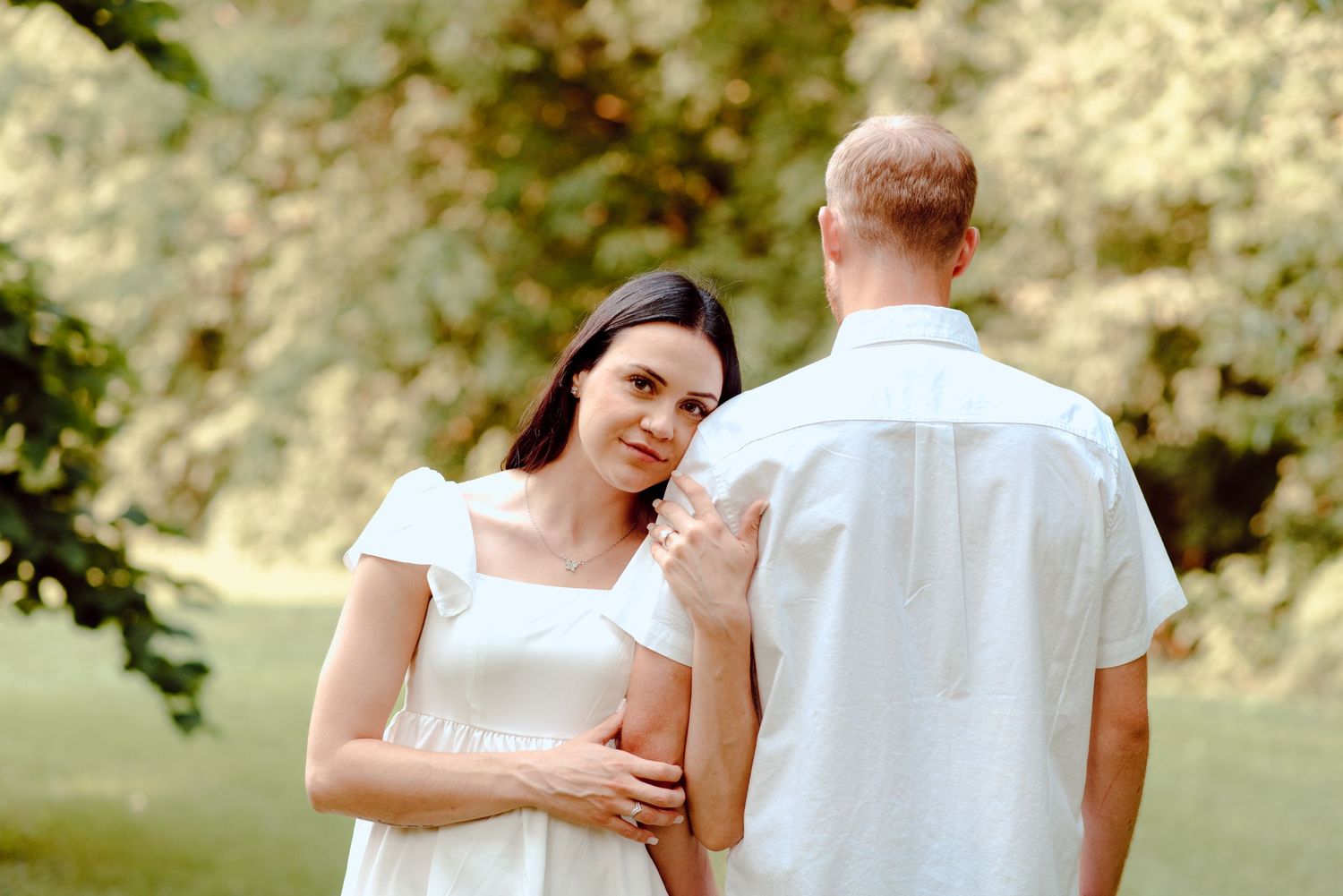 A couple shares an intimate moment in a sunlit garden setting.