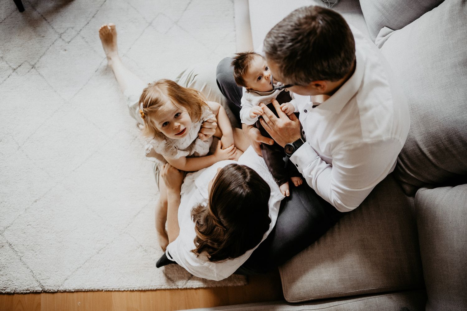 Overhead view of family playtime with dog on white floor.
