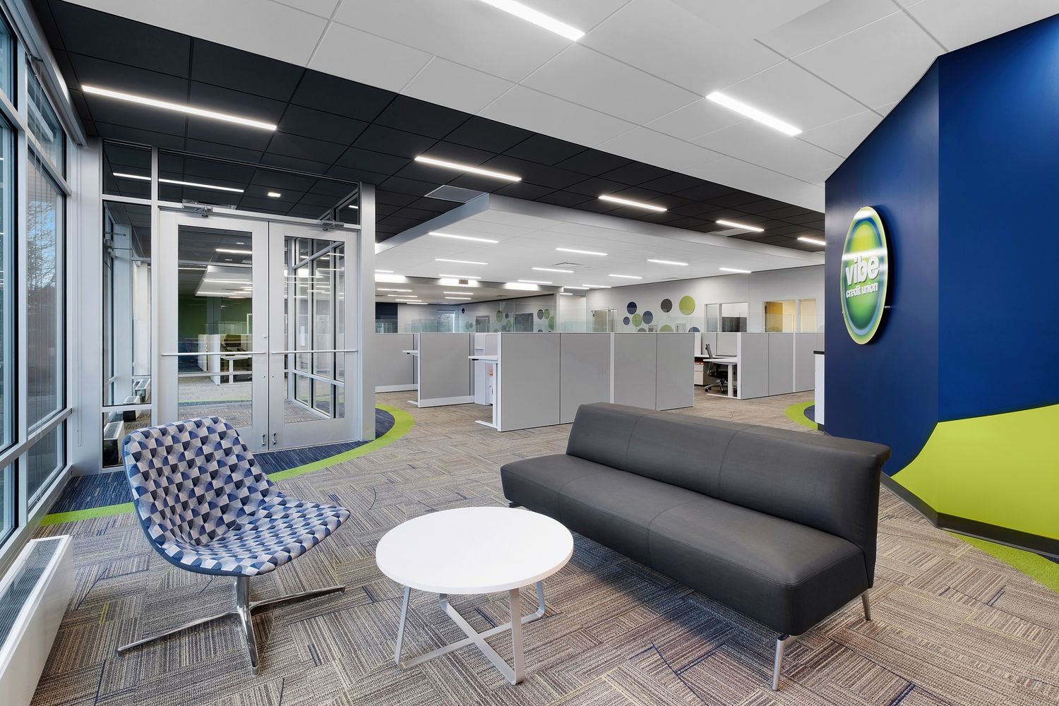 Modern office lounge area featuring contemporary seating and blue accent wall.