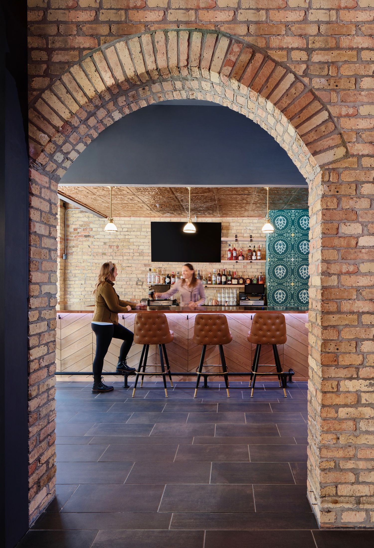 Stylish bar area with exposed brick walls and arched entryway.