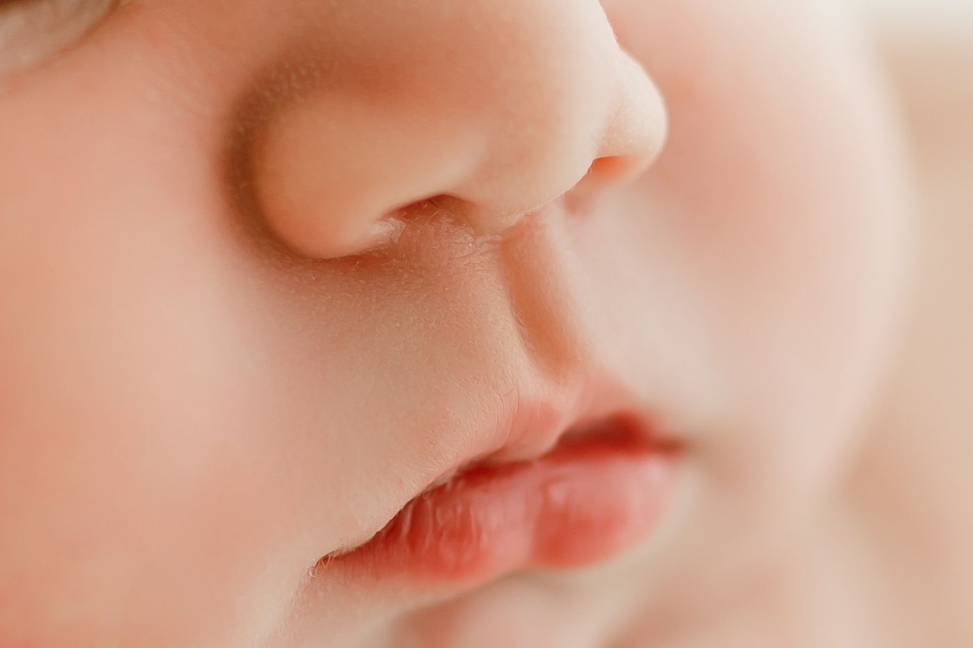 Extreme close-up of a baby's nose and lips in soft lighting.