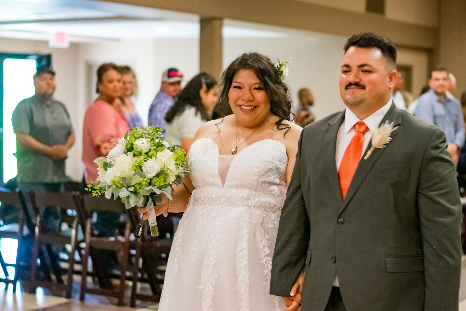 Wedding ceremony in a bright indoor venue with floral decorations and formal attire.