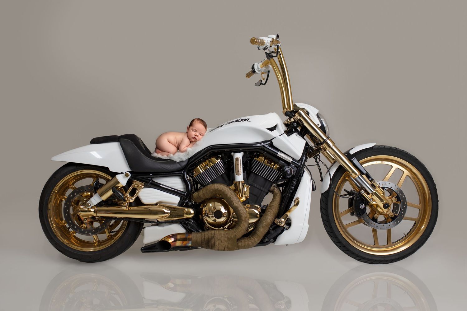 Creative newborn photography Springfield Lakes – baby safely composited onto white and gold motorcycle using Photoshop. Professional Ipswich
