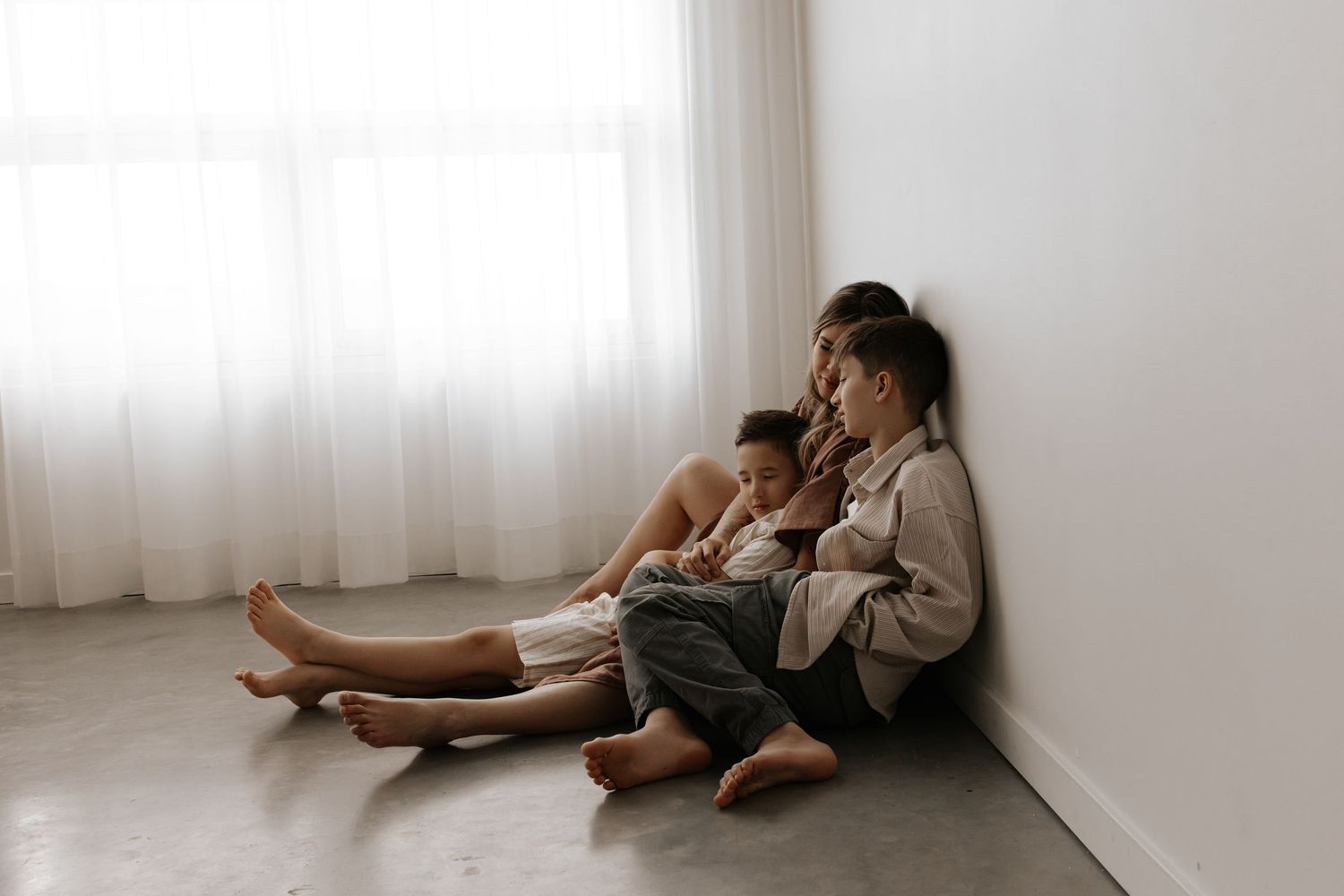A series of intimate black and white photographs showing tender moments between two people in a minimalist room setting.