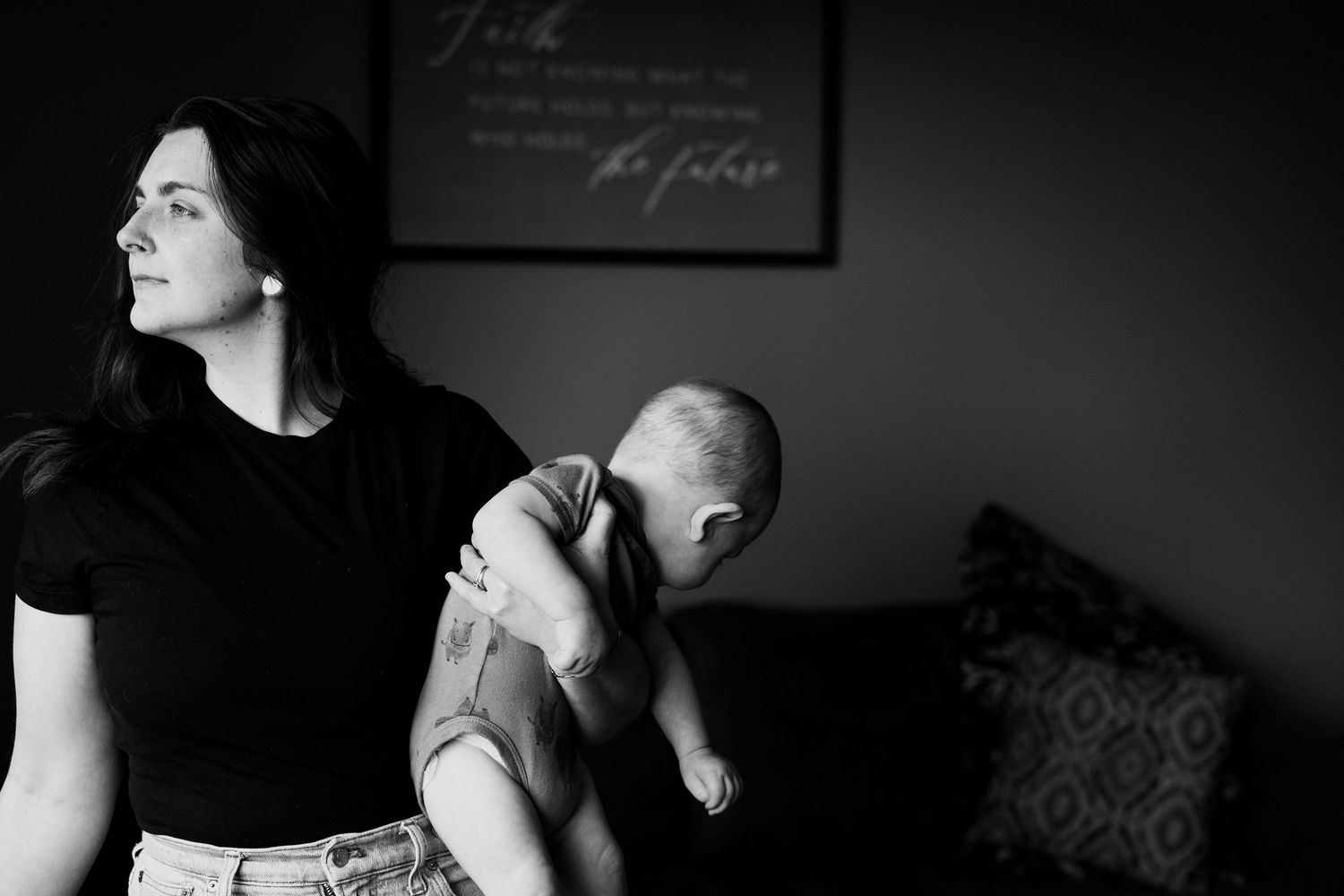 Black and white photo of mother holding her newborn near a window at home | in-Home Family Photos in Westminster, CO