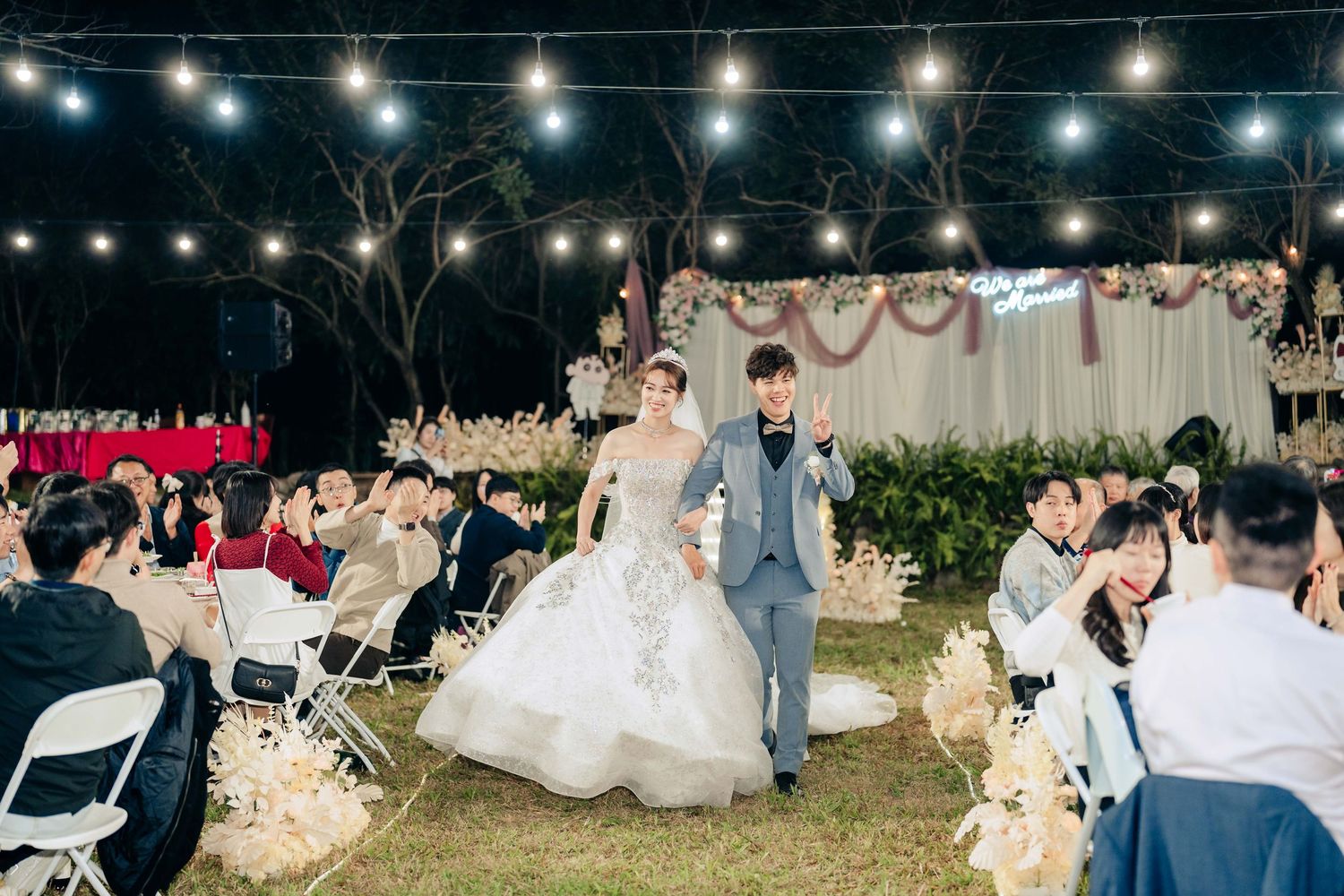 屏東自宅婚禮，結合戶外證婚與傳統流水席形式，於新人家中與田野環境舉行。從白天自然光下的互動拍攝，到草地證婚儀式與晚間燈串流水席宴客，呈現屏東戶外婚禮的自由與溫度。畫面包含田間散步、新人進場、親友觀禮與流水席互動等，展現紀實婚禮攝影風格，適合尋找自宅婚禮與戶外流水席婚禮的新人參考。