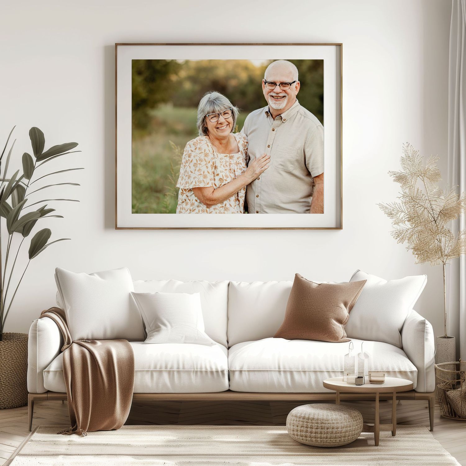 Framed photo of a smiling elderly couple displayed above a white sofa in a bright, modern living room.