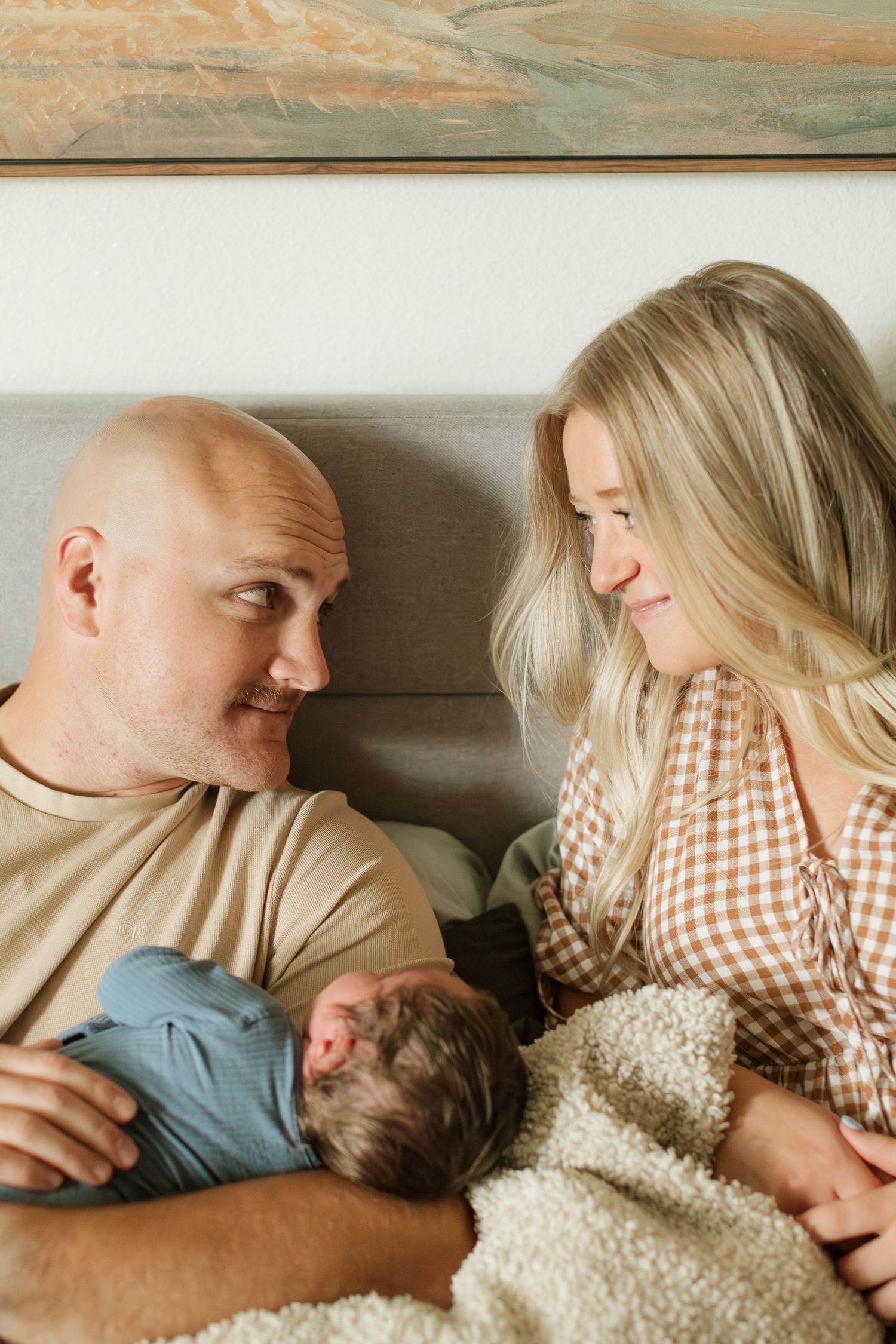 mom and dad look at each other lovingly with newborn baby boy between them