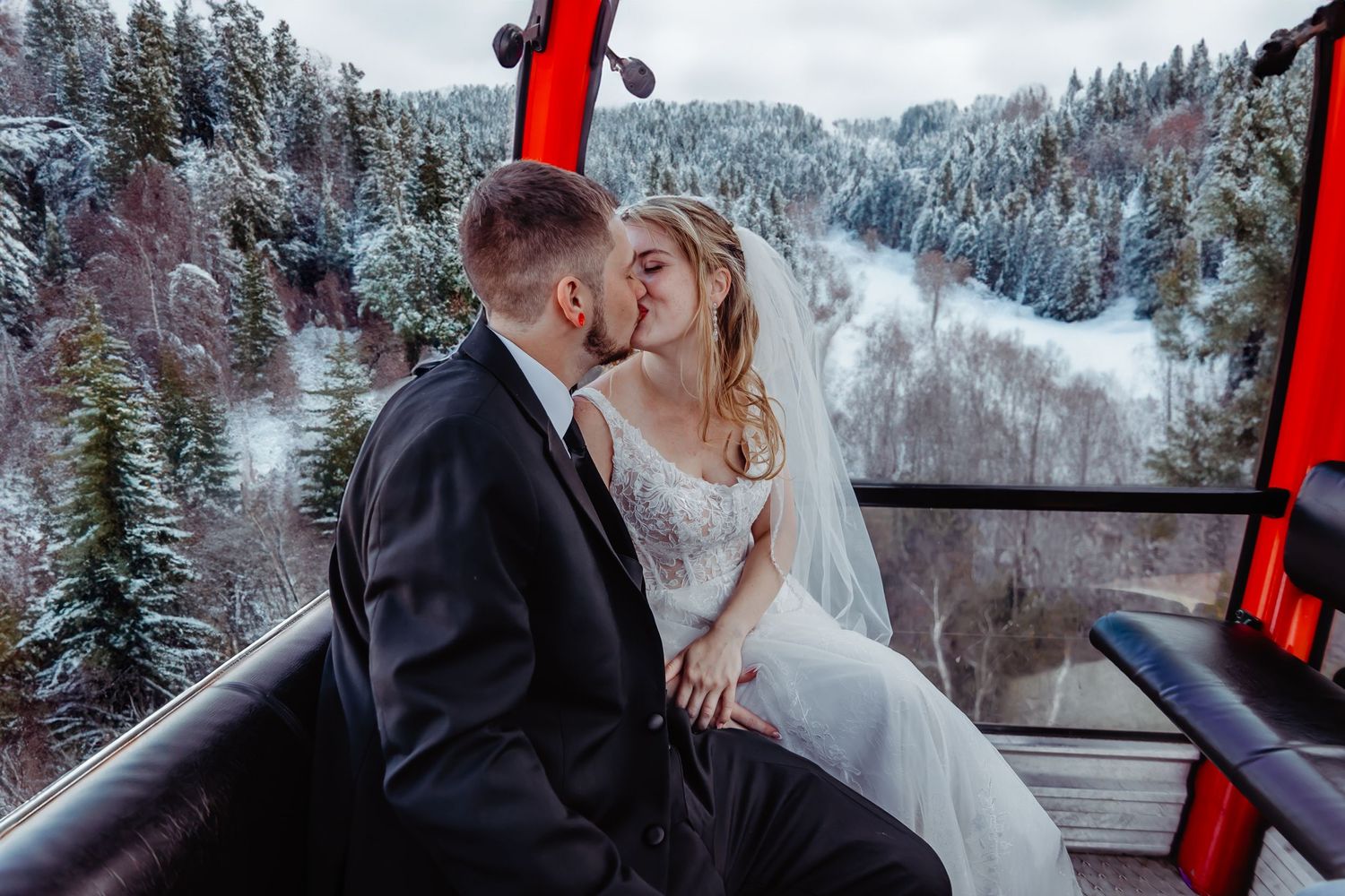 A winter wedding moment captured in a ski lift gondola against a snowy mountain backdrop.