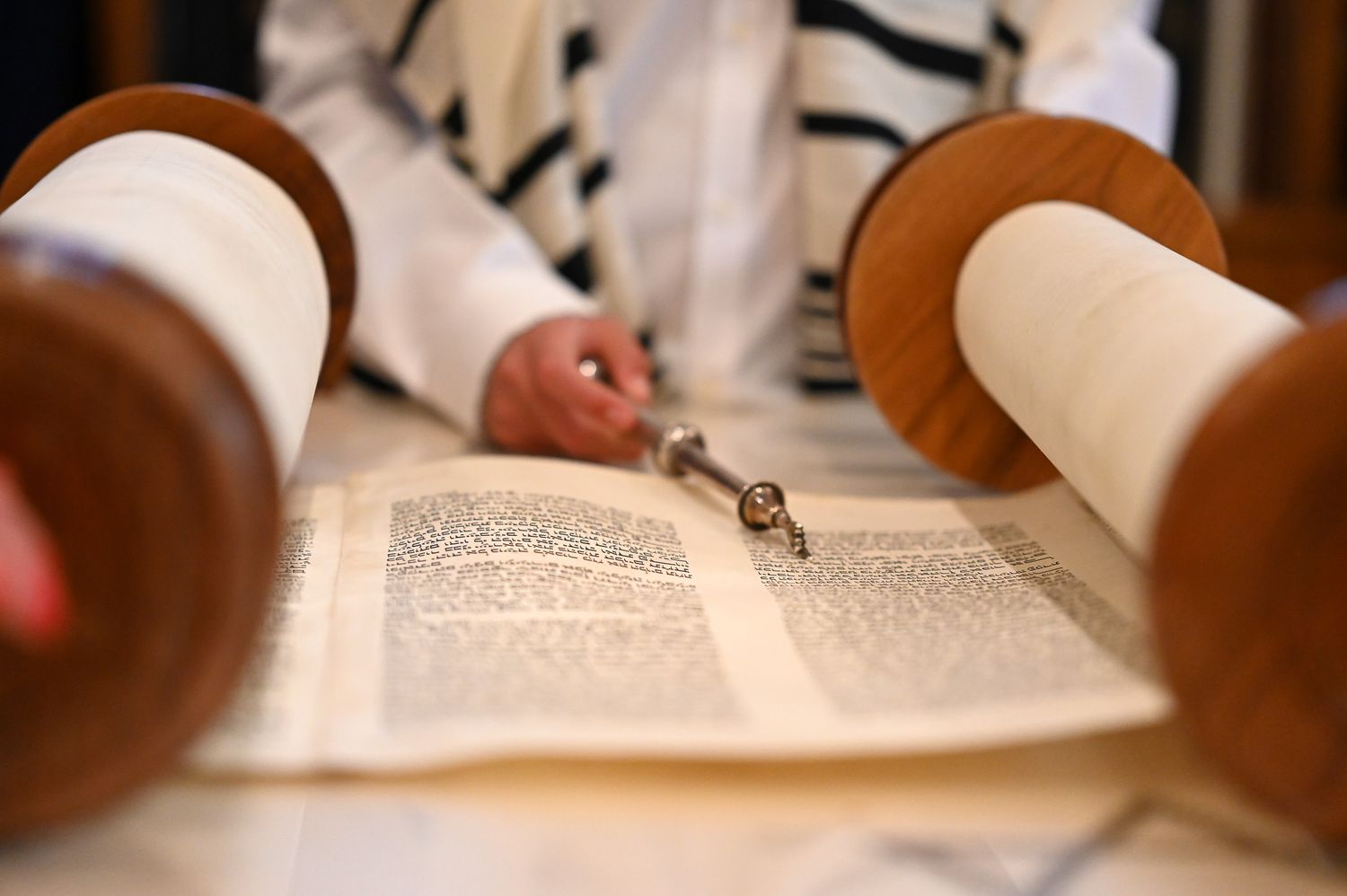 Young boy reading from the Torah scroll while standing on the bimah in a synagogue.