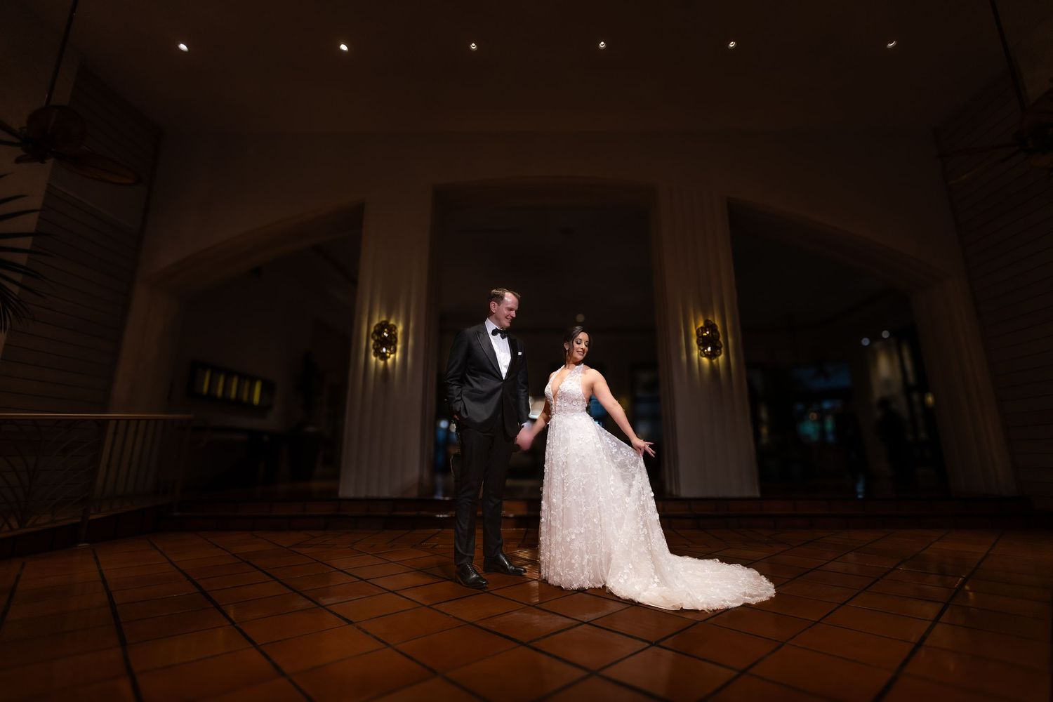 Elegant white wedding dress displayed on a staircase surrounded by tropical landscaping and palm trees.