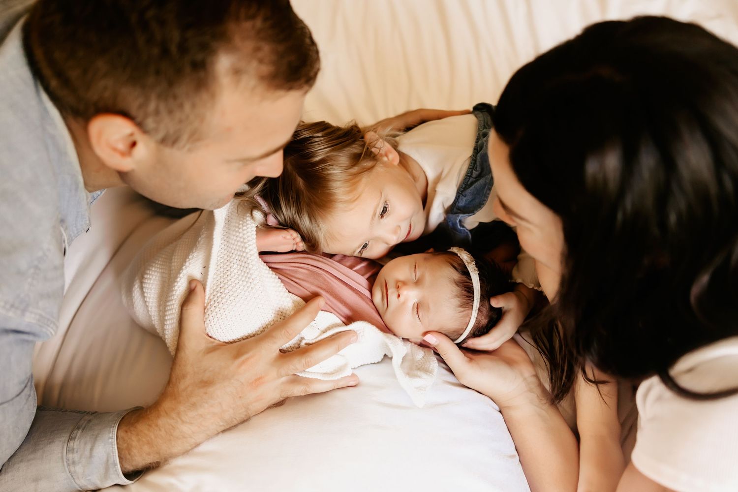 A family snuggles their newborn baby girl as a Honolulu Newborn photographer captures them during their in home newborn session.
