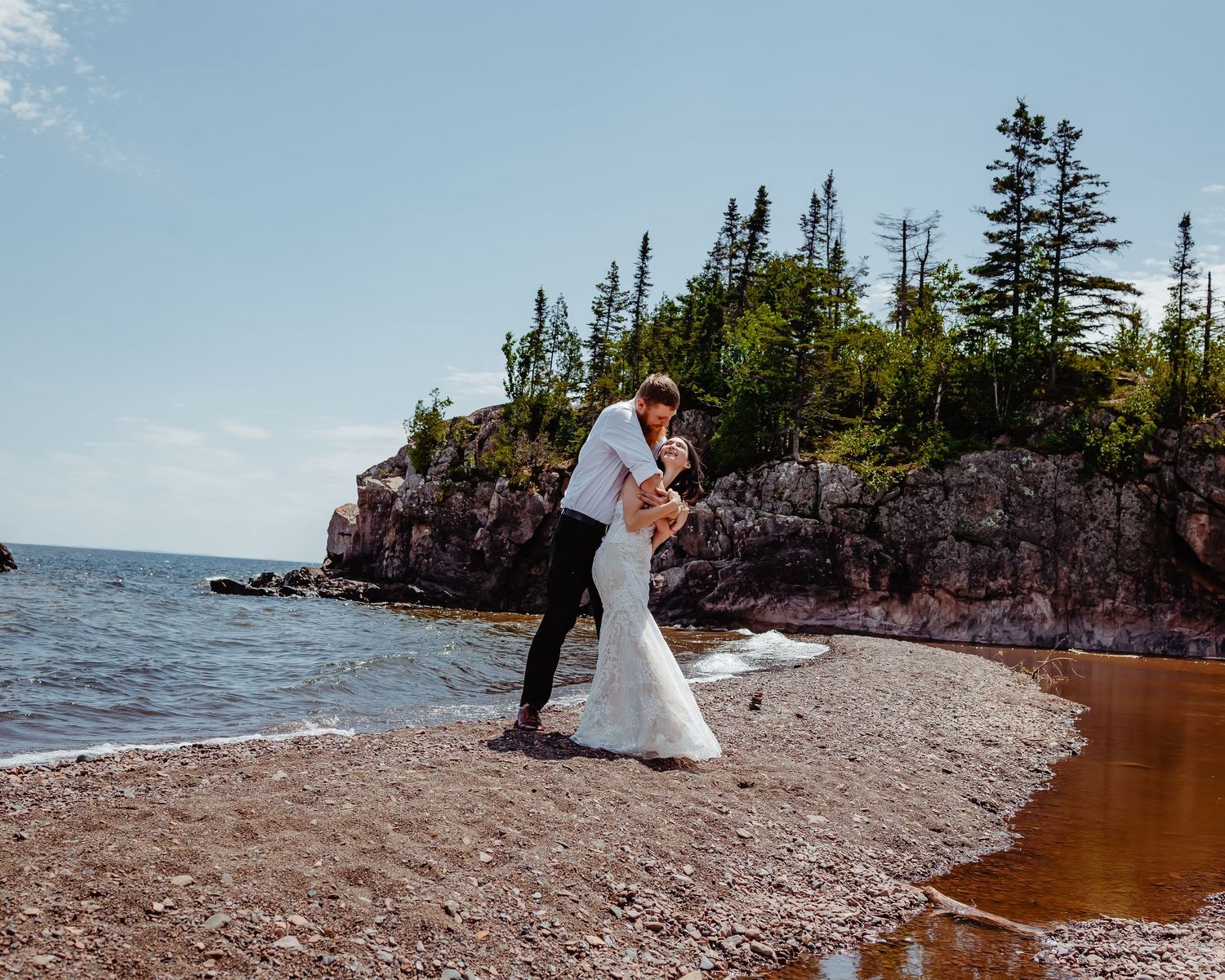 Beach wedding ceremony with rocky cliff backdrop on Lake Superior shore.