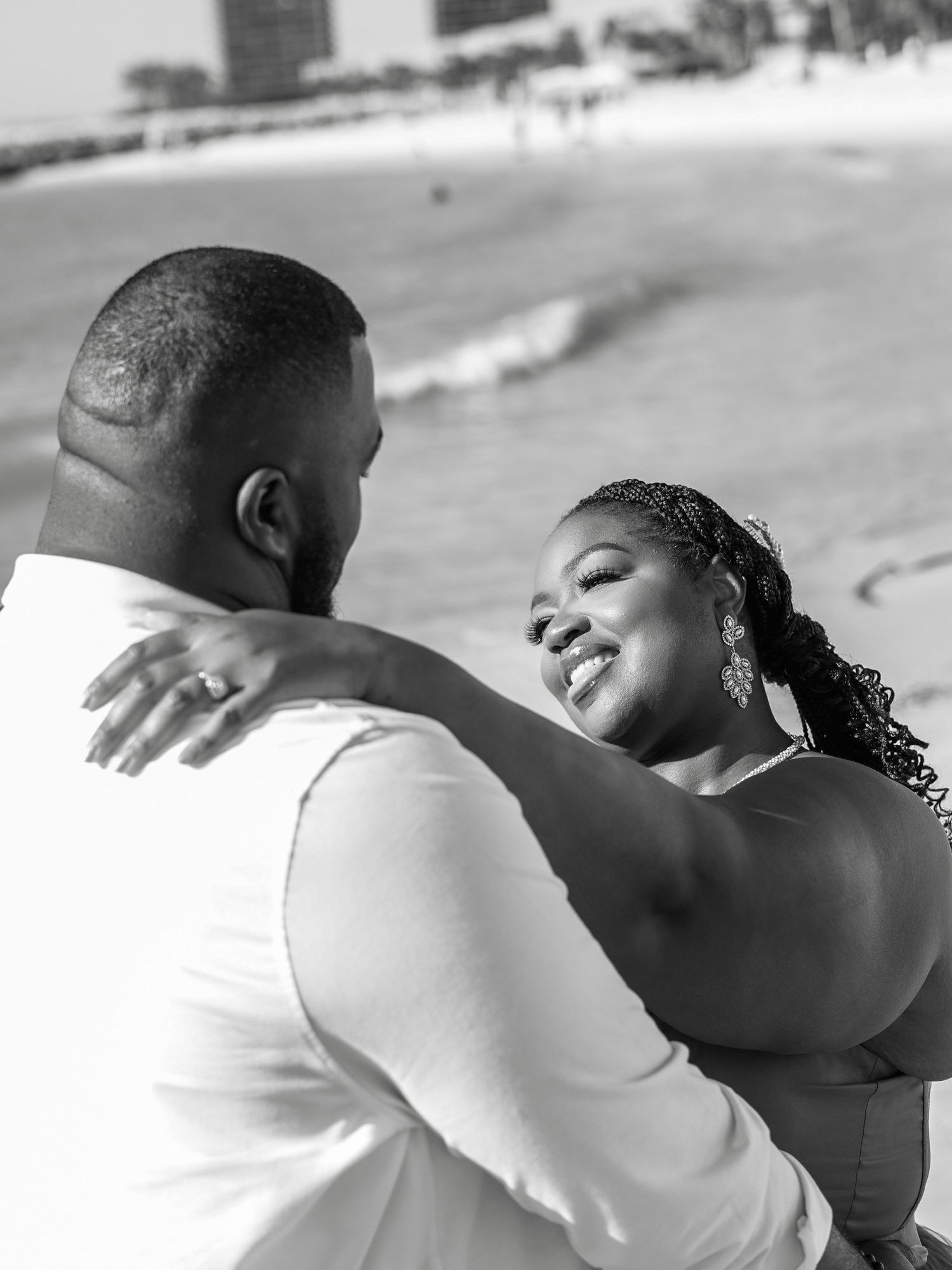 A loving couple shares an intimate dance moment together on the beach in black and white photography.