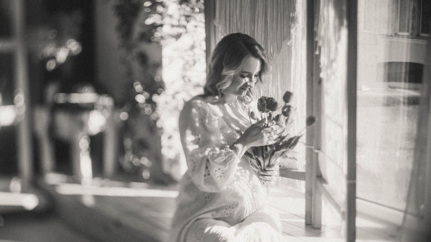Black and white cinematic photo of a pregnant woman with flowers.