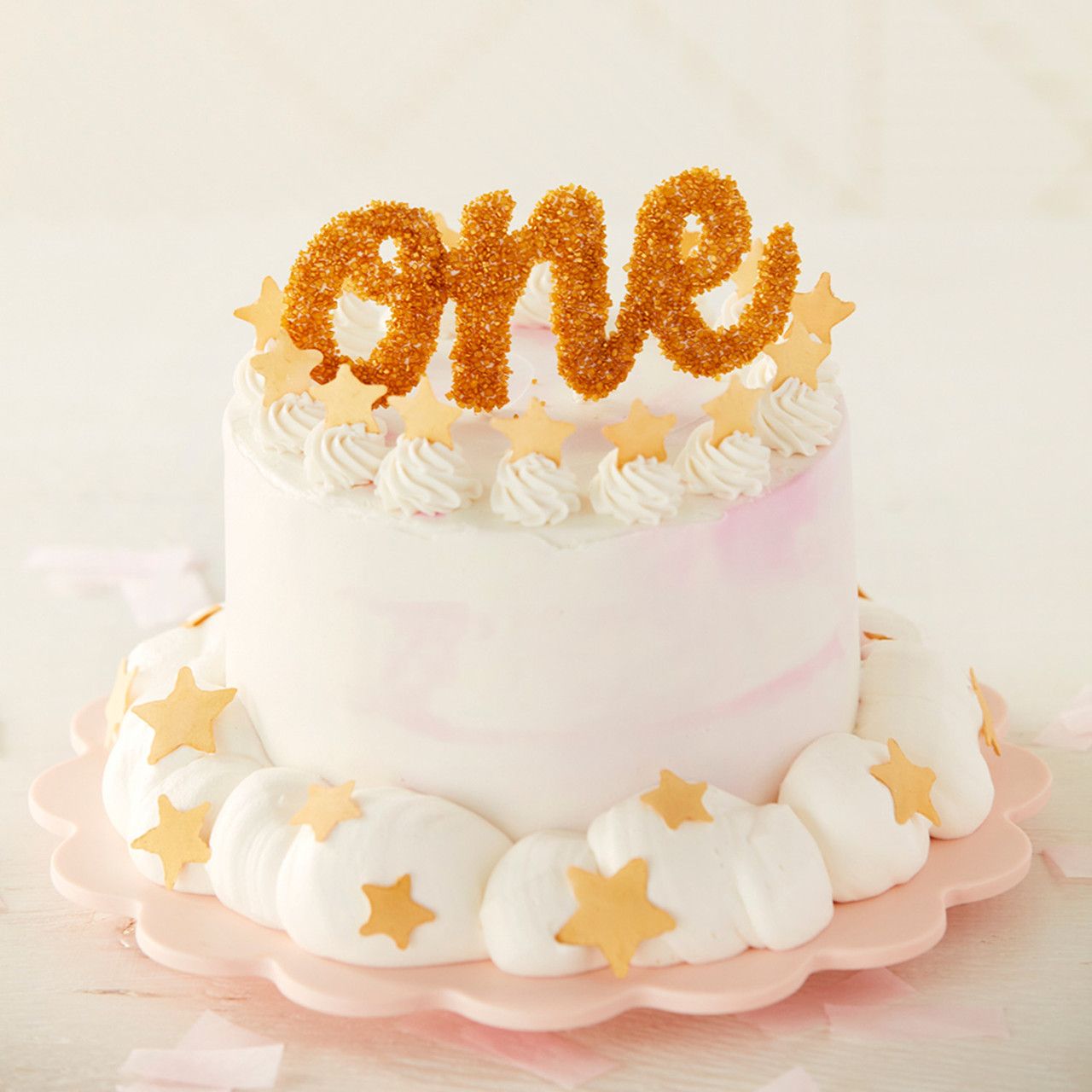 First birthday smash cake in light colors with the word one