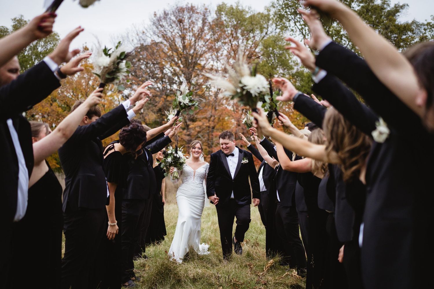 A romantic wedding couple embraces on a wooden bridge surrounded by vibrant fall foliage in golden autumn colors.