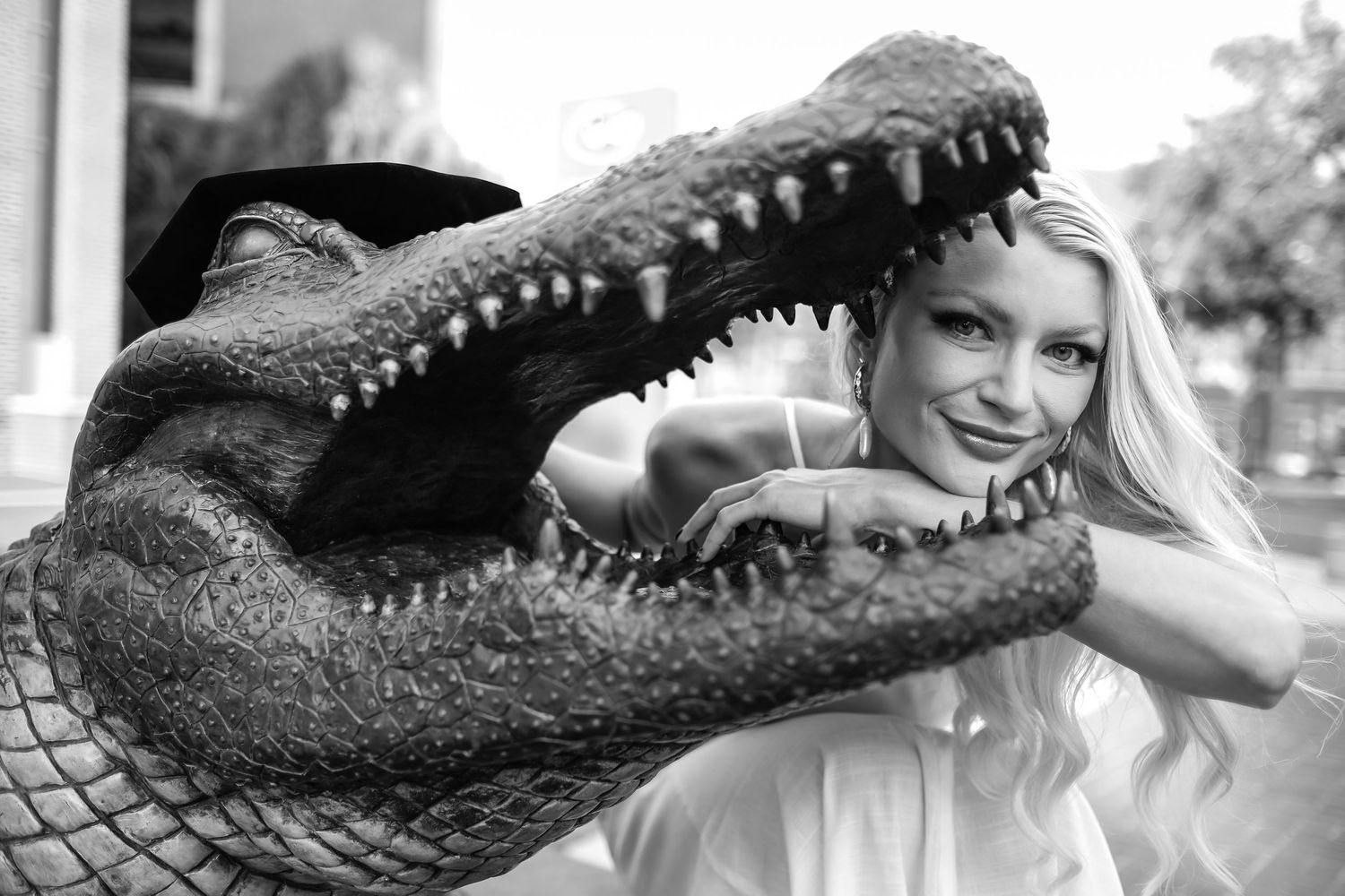 A black and white photograph of a UF grad smiling with the Bull Gator in Gainesville, Fl.