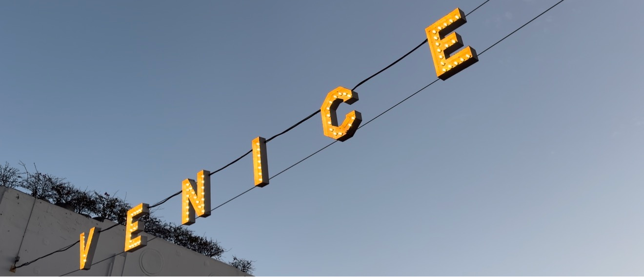 Yellow letters mounted on poles against a blue sky create a striking graphic element in an urban setting.