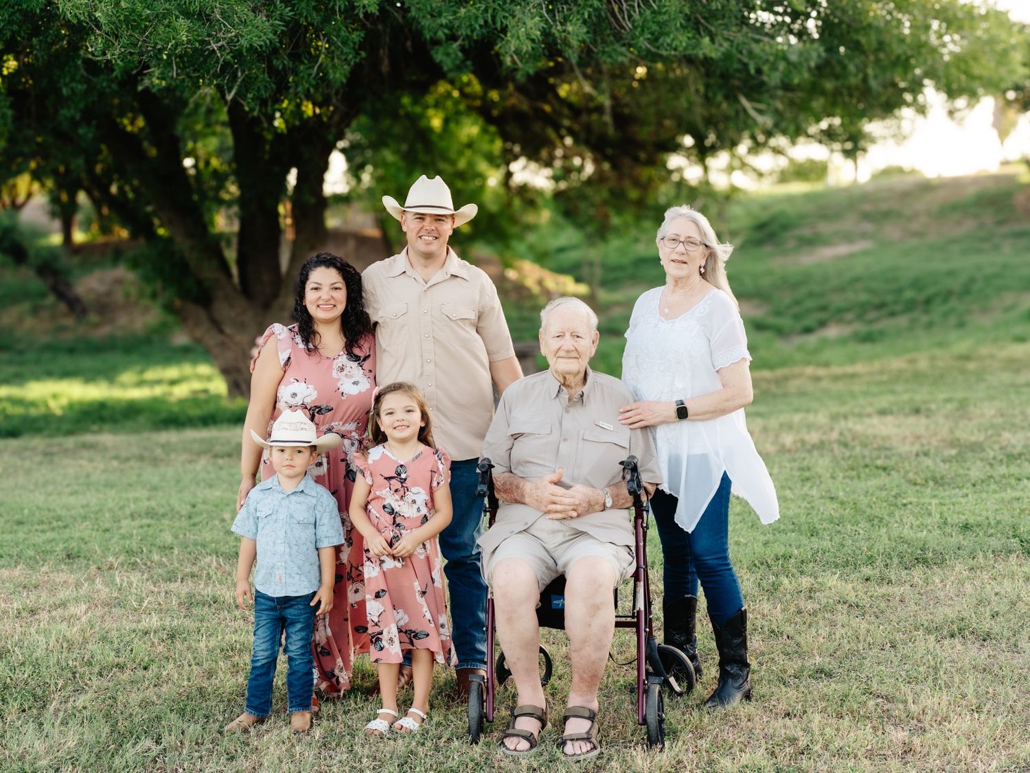 A group of people walking and laughing together in a grassy field during golden hour sunlight.