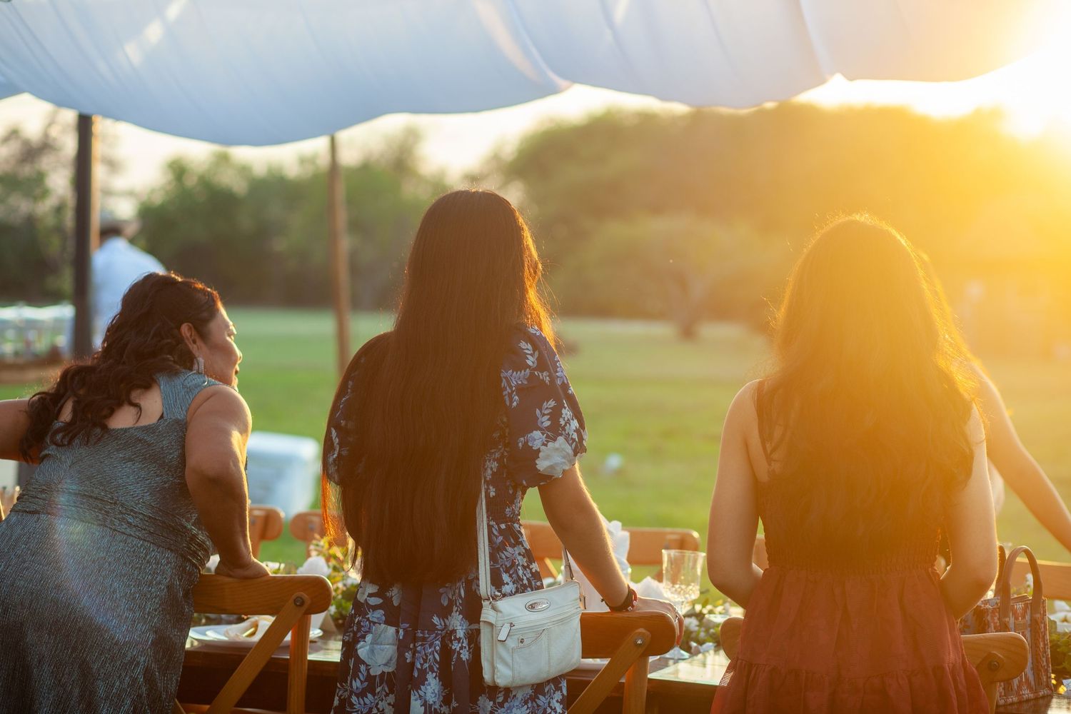 People enjoying drinks at an outdoor gathering during golden sunset hour in a park setting.
