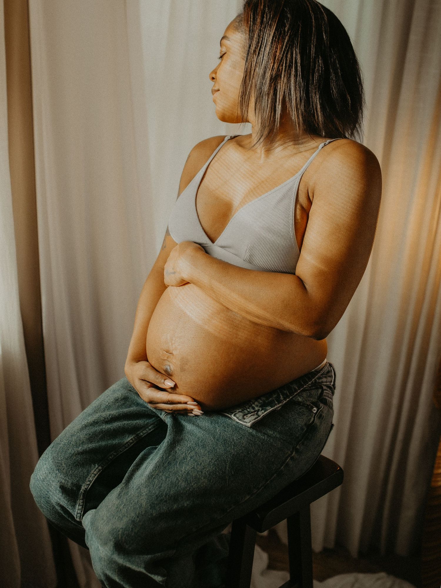 Artistic nude boudoir photo series showing silhouette against beige curtains in warm lighting. maternity , pregnancy photographer