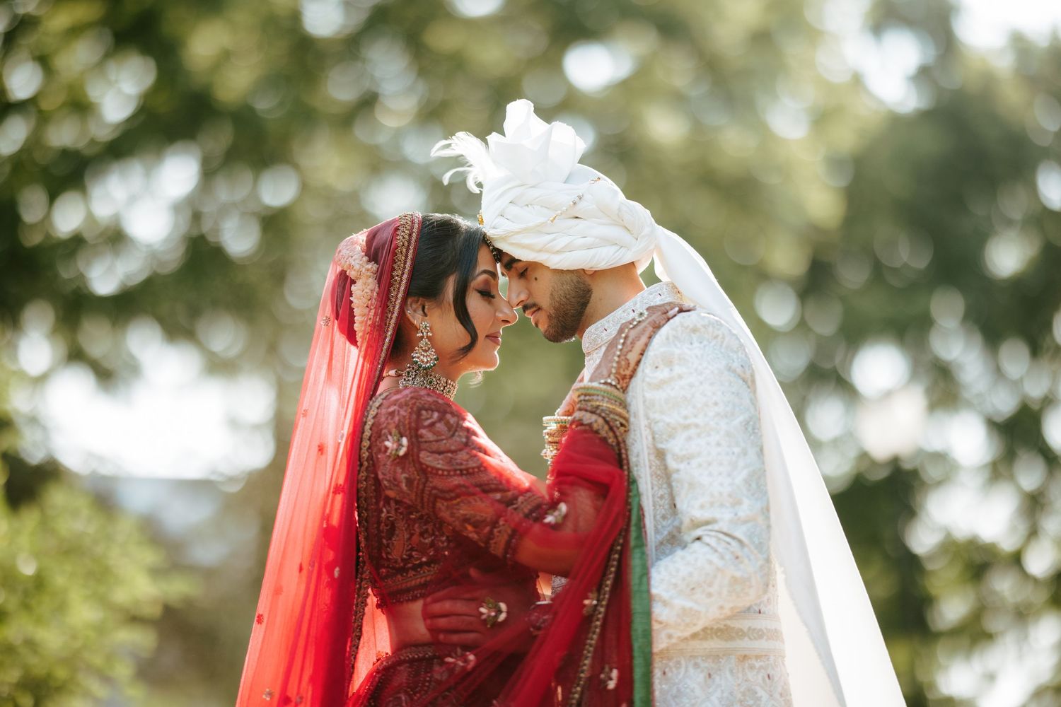 A couple in traditional Indian wedding attire shares romantic moments during their outdoor wedding ceremony.