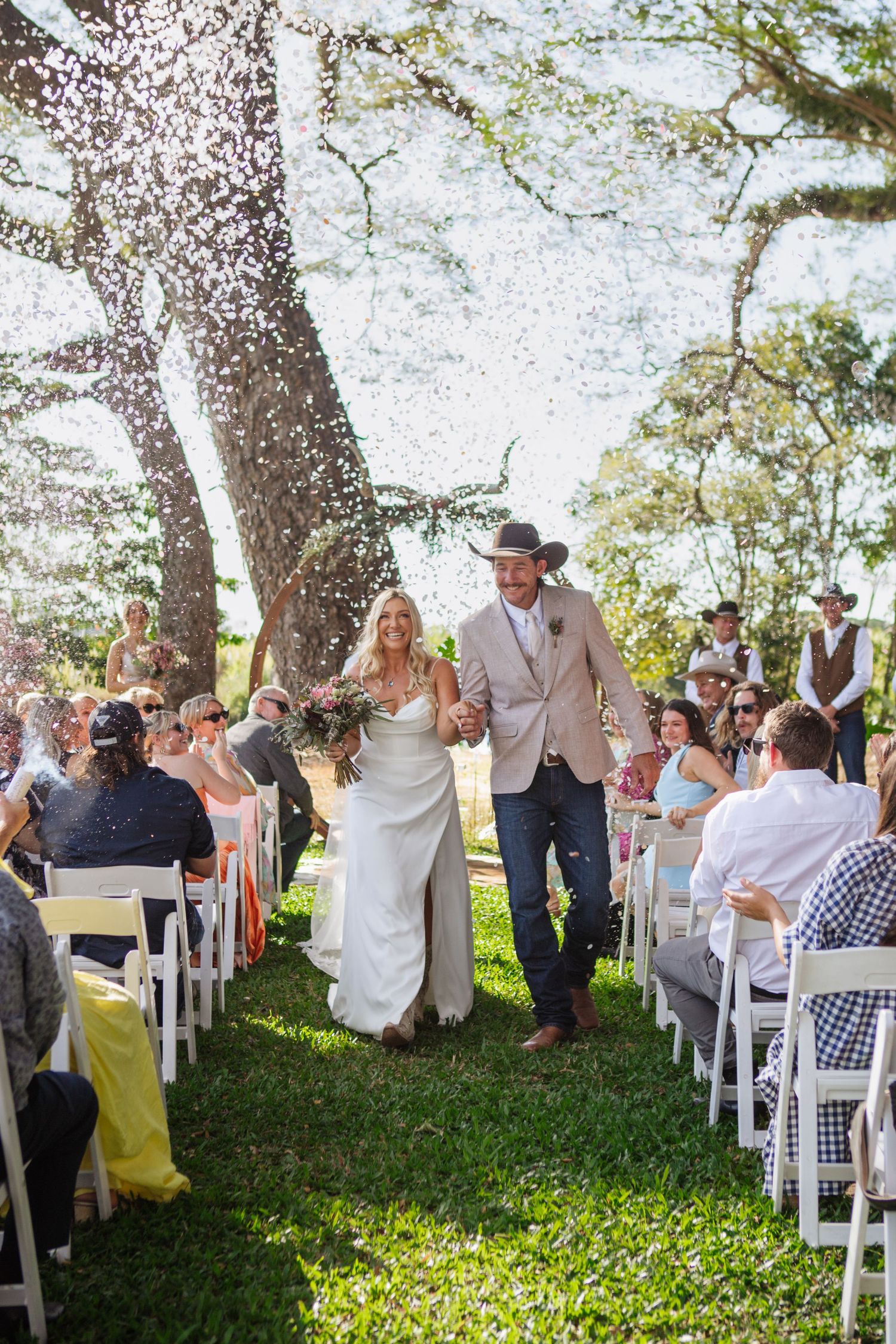 bride and groom walking down aisle in confetti at port douglas wedding