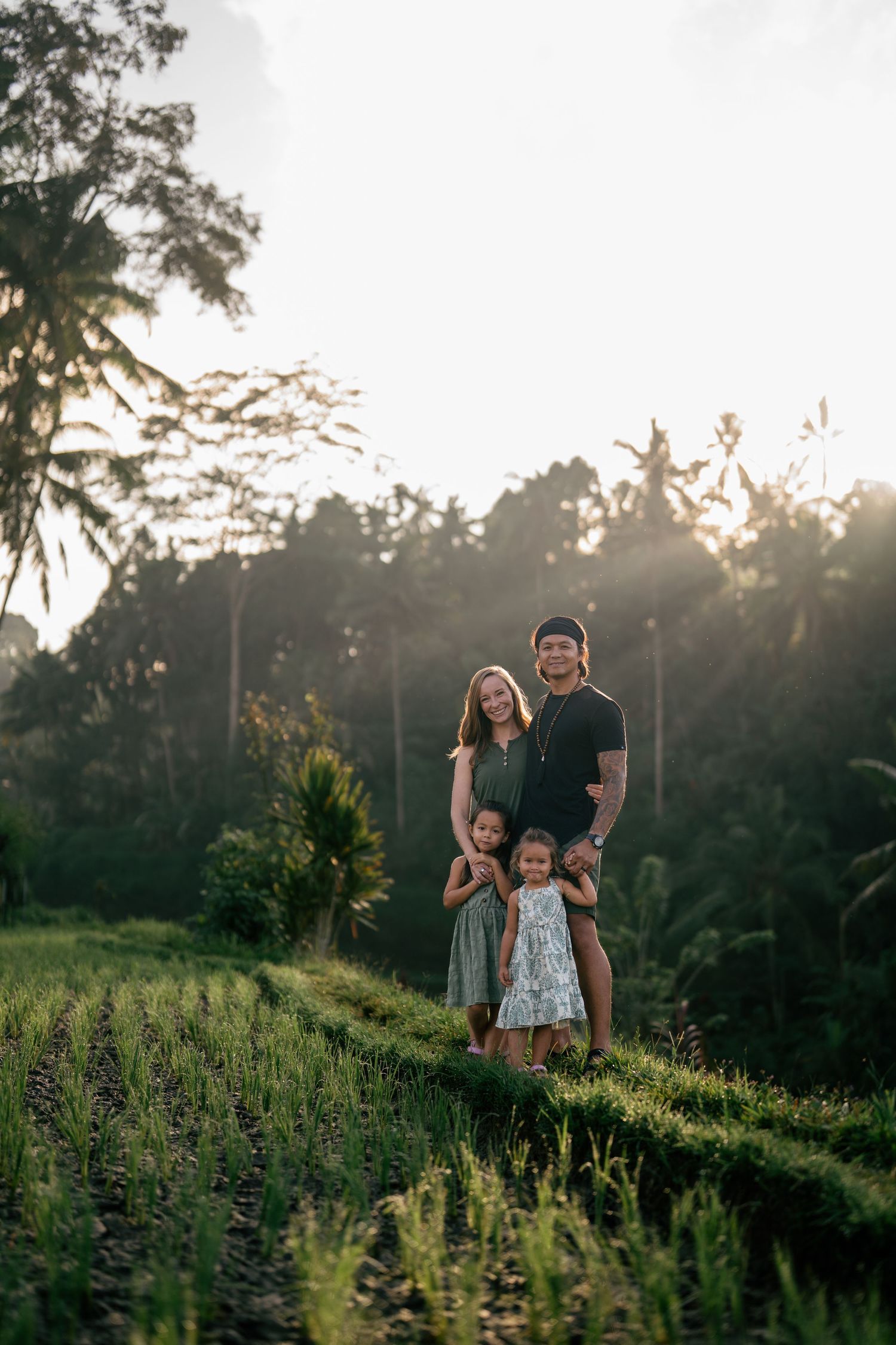 A couple walking through a sunlit grassy hillside at sunset in Hawaii.