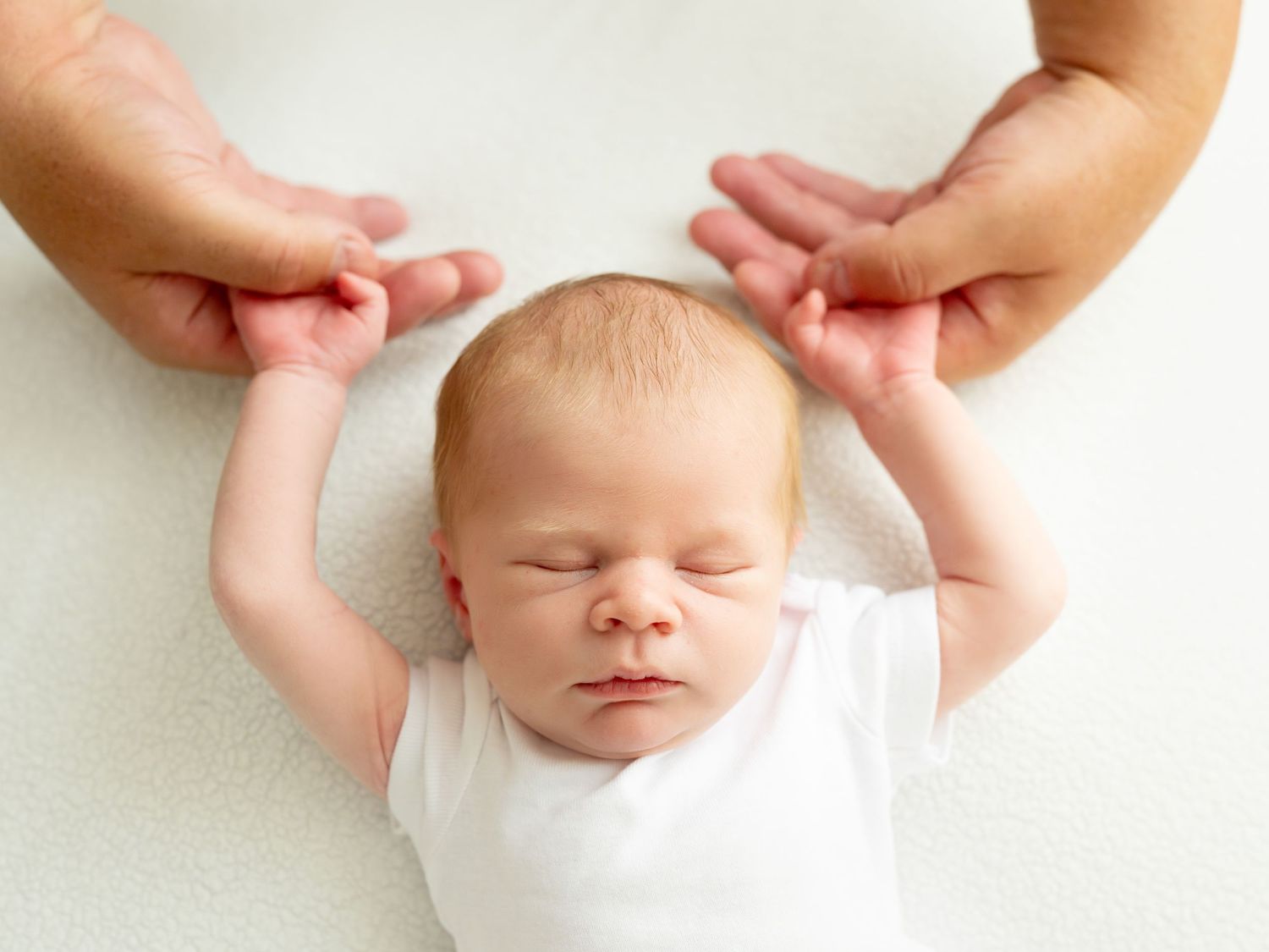 A baby receiving a gentle head massage with hands applying pressure to different points on the scalp.