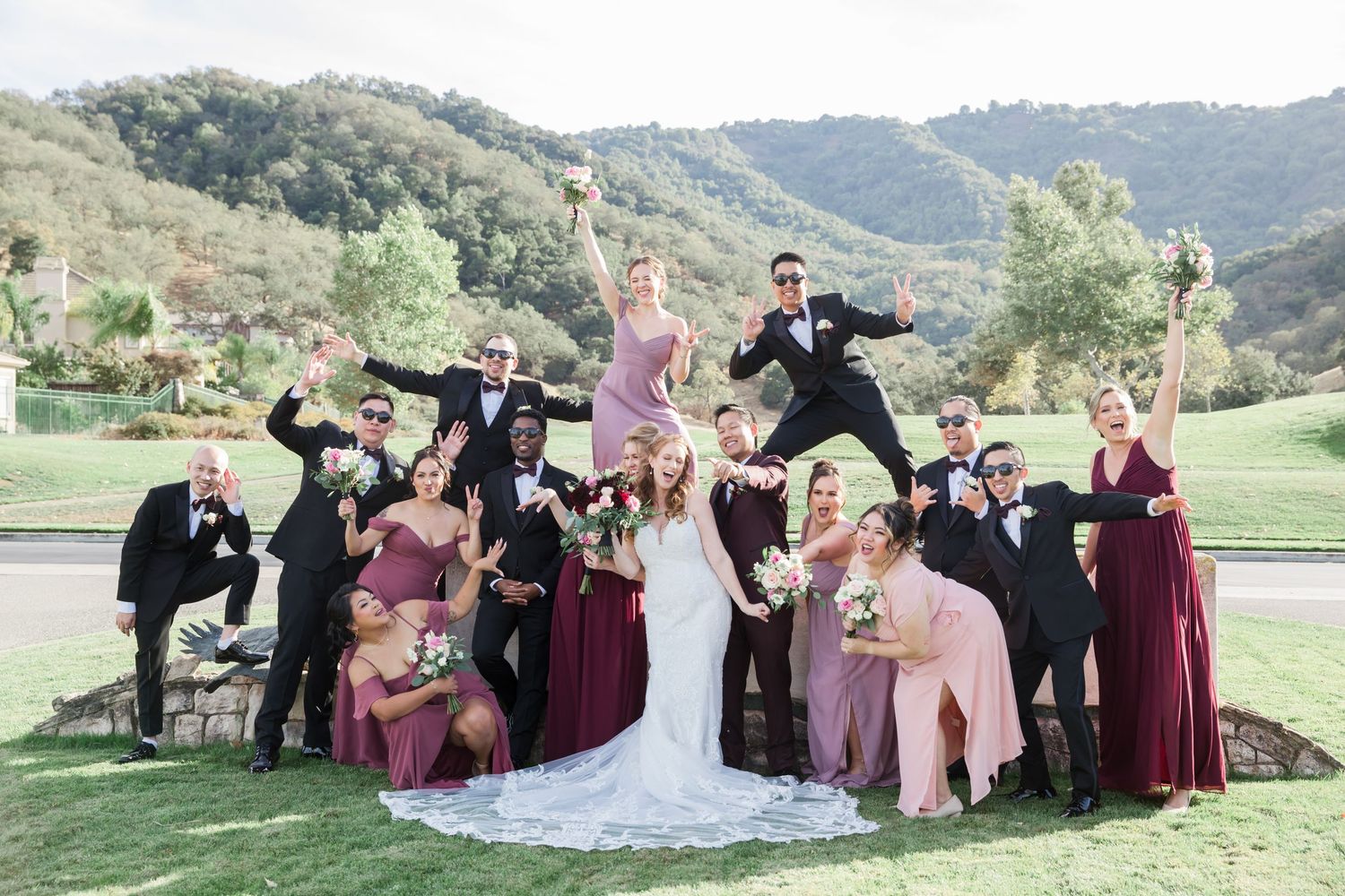Wedding party poses for playful and candid group photos in a scenic mountain landscape setting.