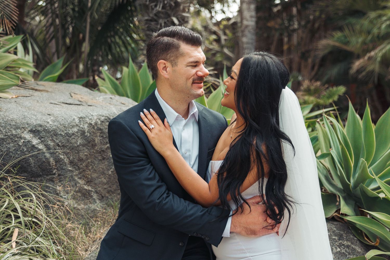 Romantic wedding couple embracing in a lush tropical garden setting.