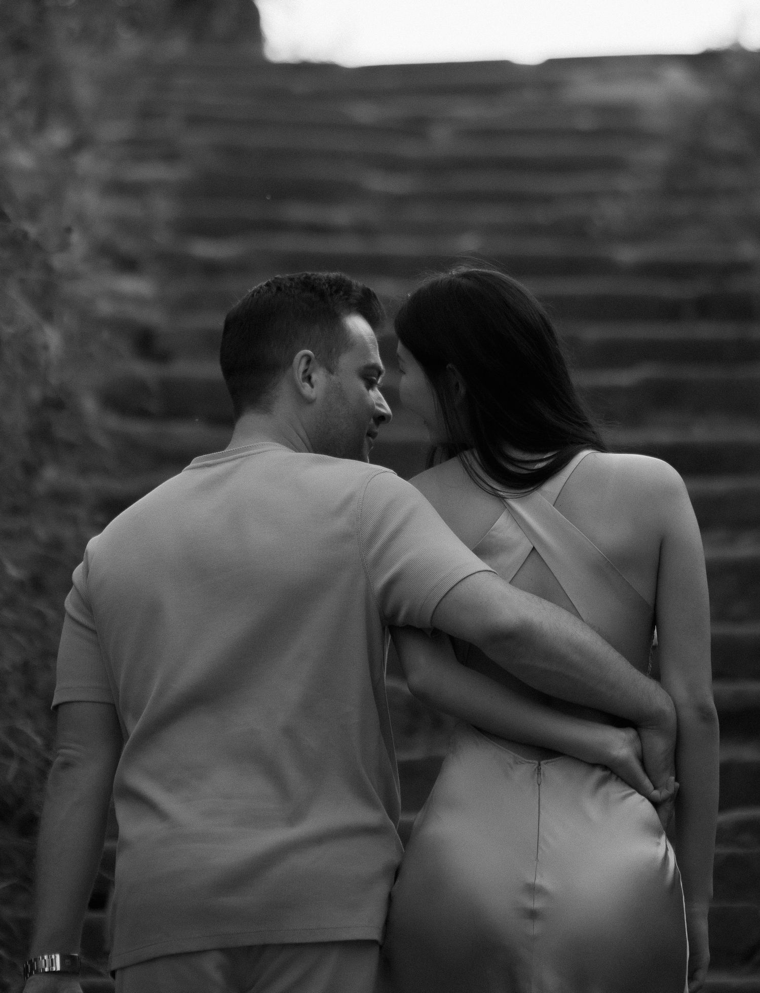 Intimate black and white portrait of couple embracing on stone steps.