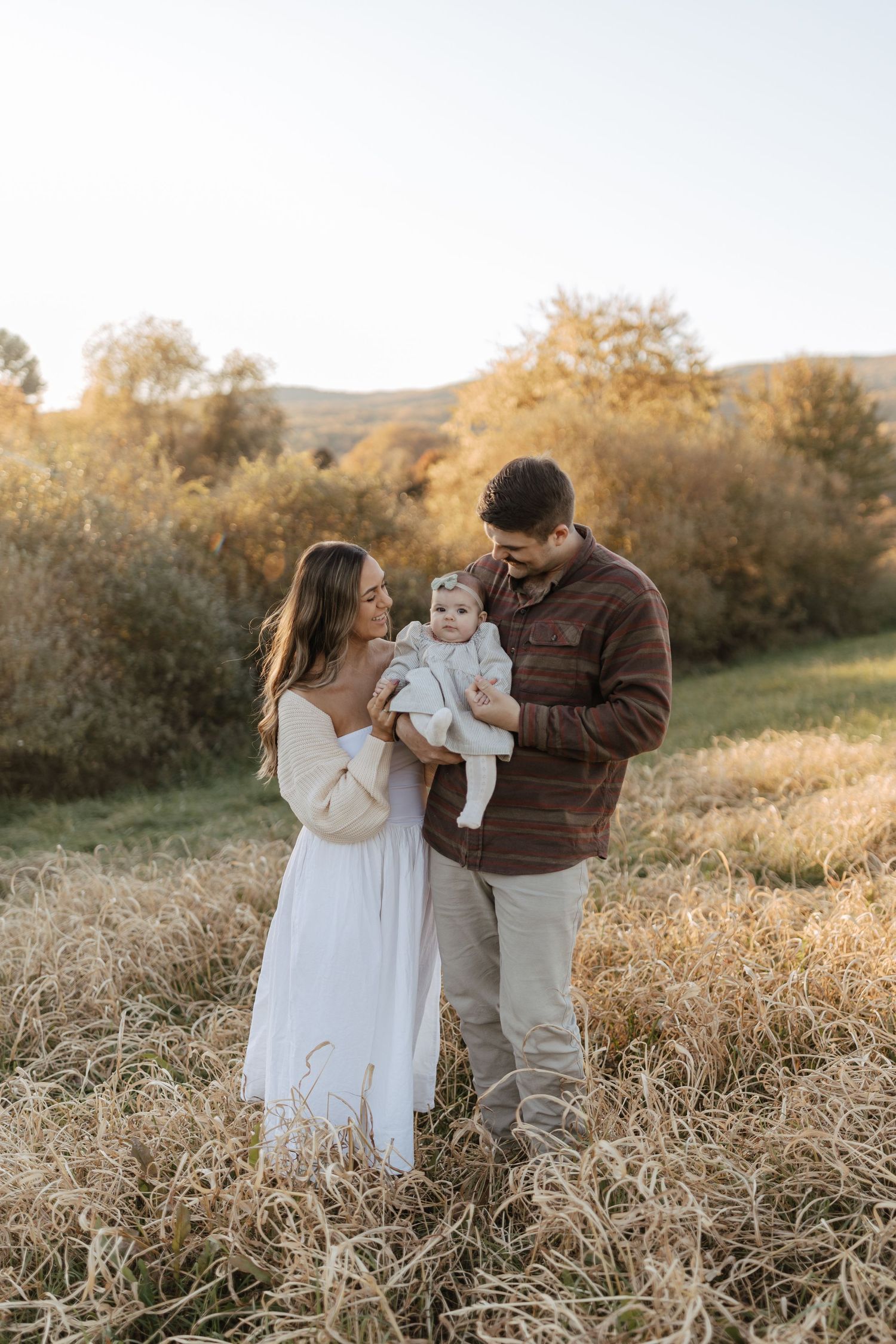 A tender family moment captured during golden hour in a rustic autumn field.