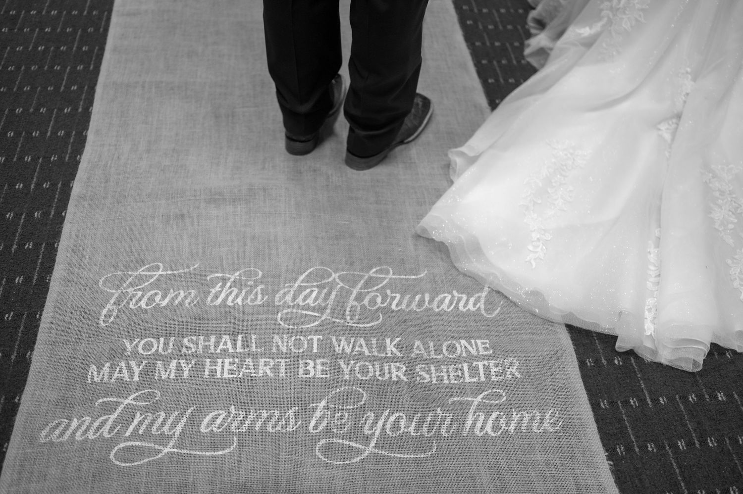 A black and white photo of wedding text on the floor next to a bride's dress.