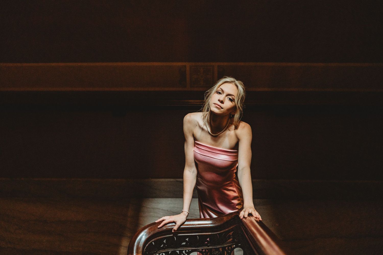 Dramatic indoor photoshoot with moody lighting and dark background.