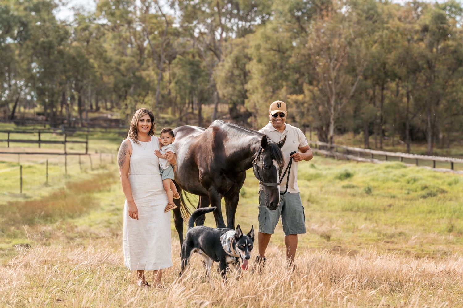 a mom holding a one year old and dad is leading their horse while their dog is walking in front of them during a family photoshoot in Sydney