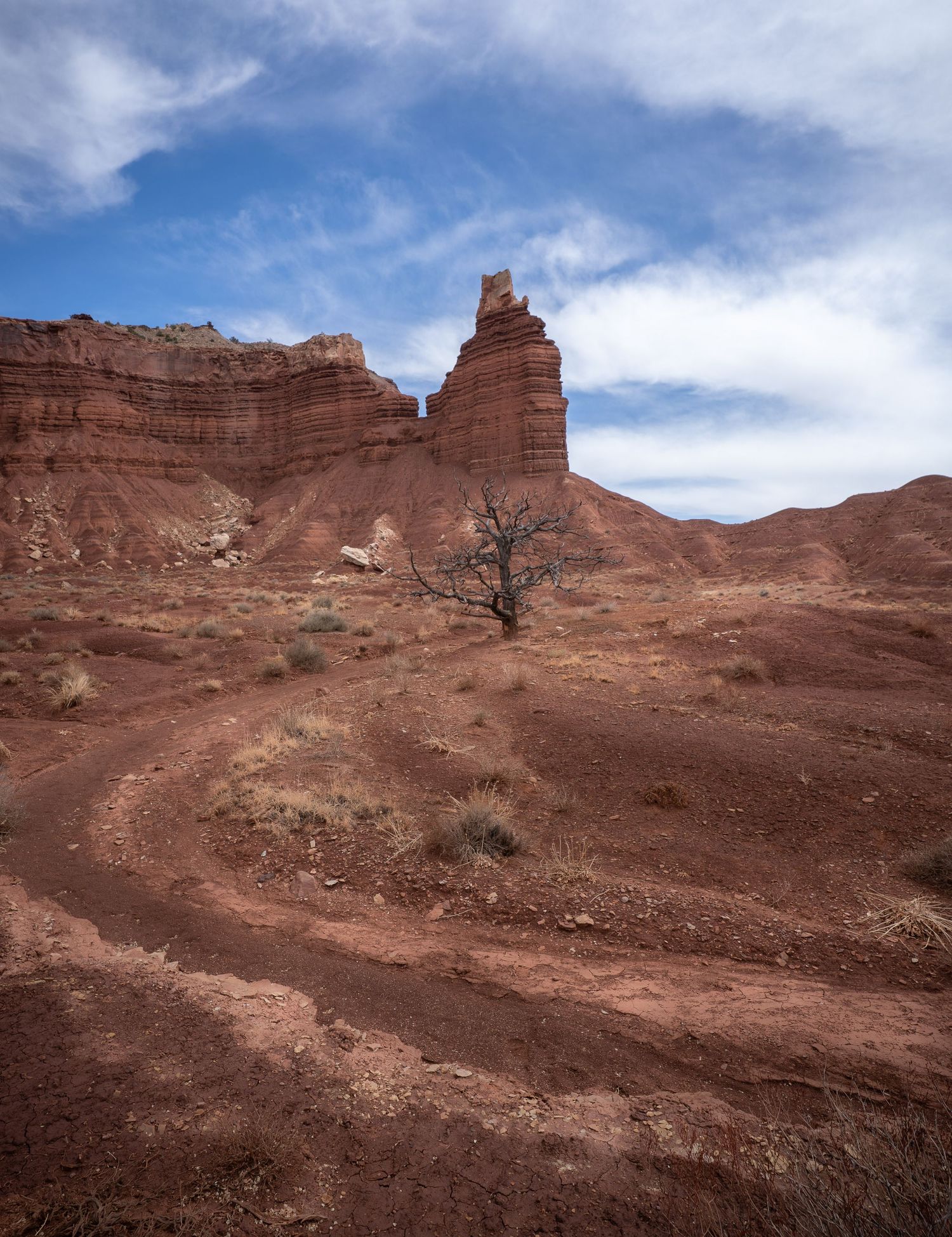 Dramatic storm clouds loom over red rock formations at Capitol Reef National Park with barren desert landscape in foreground.