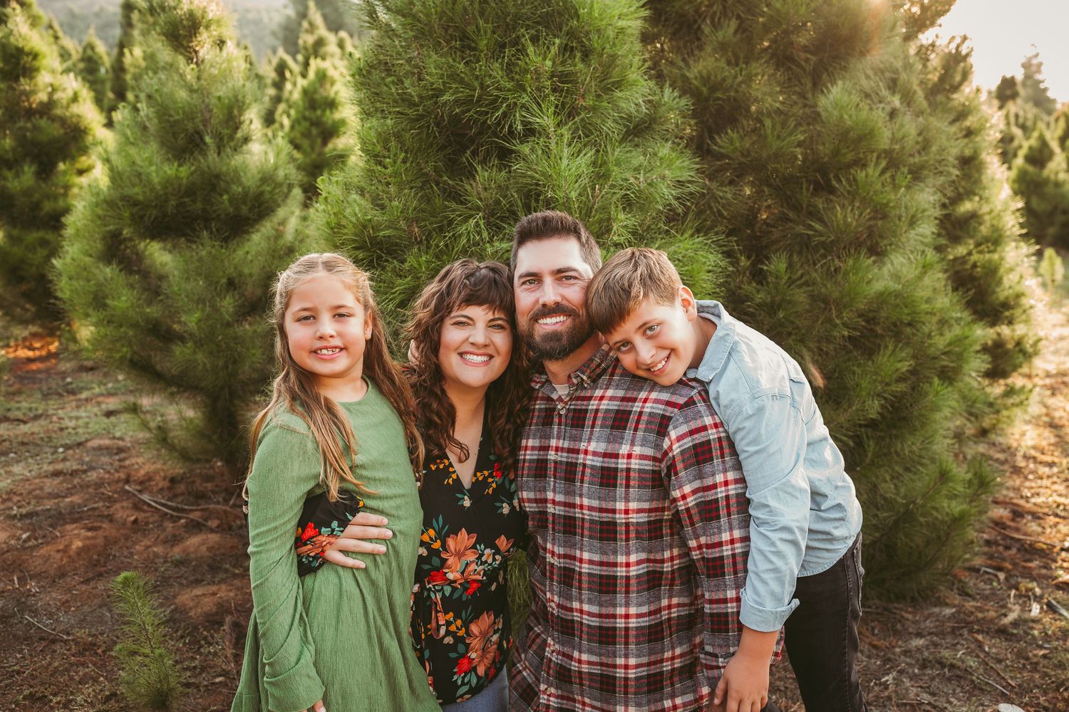 A happy group poses together in a wooded outdoor setting during golden hour.