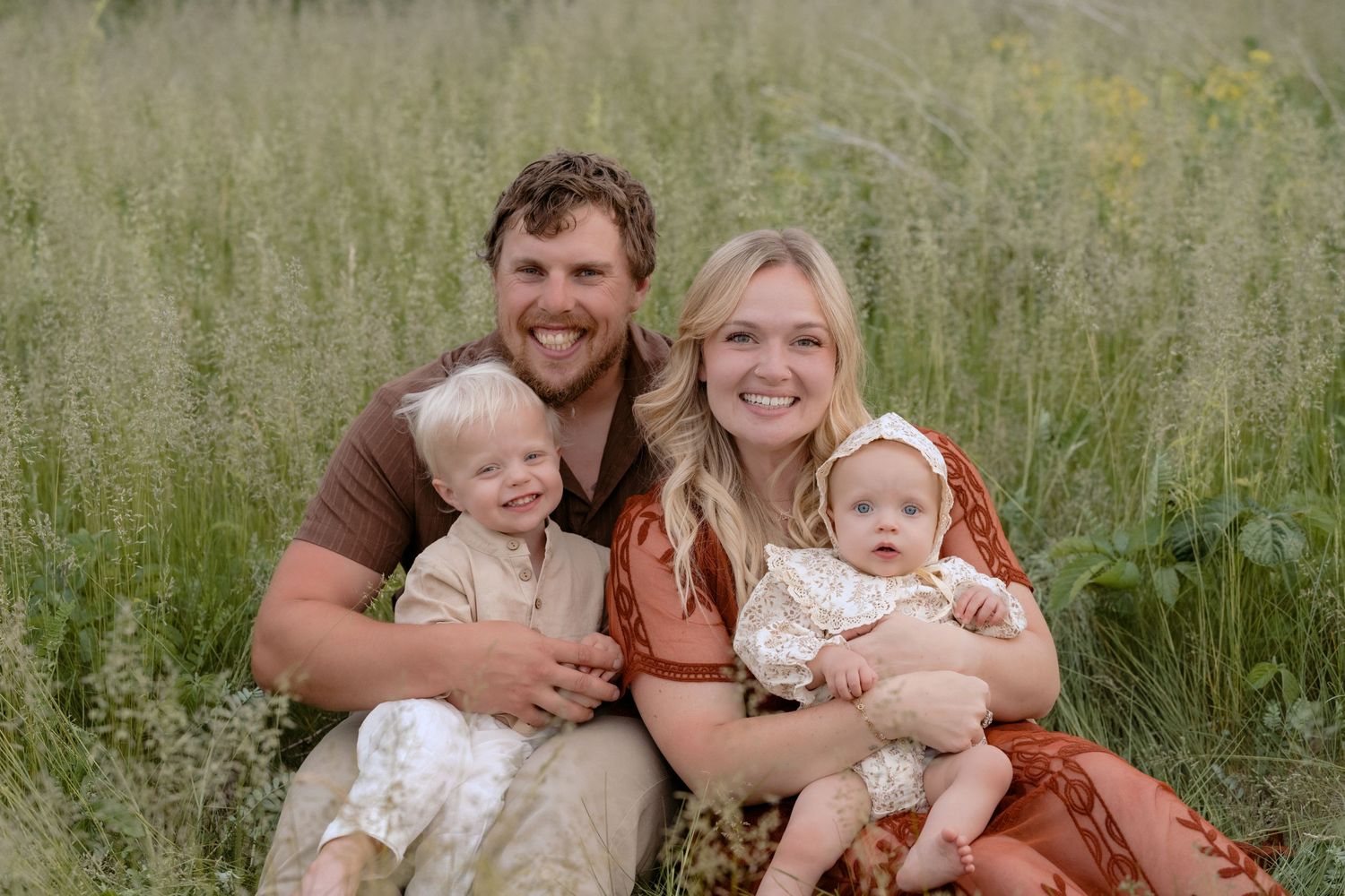 young kids running through the grasses while parents and baby follow behind during fall mini session in hudson wisconsin