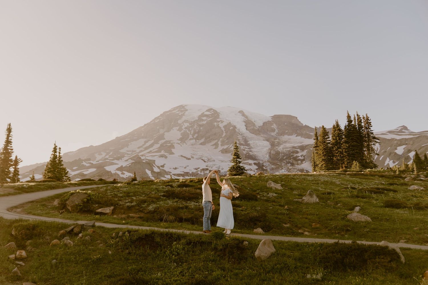 Couple eloping at Mount Rainier with snow-capped peak, evergreen trees, and golden meadows in Washington State.