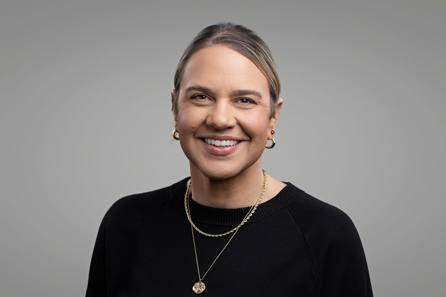 Professional studio portrait against gray background wearing light blue dress shirt.