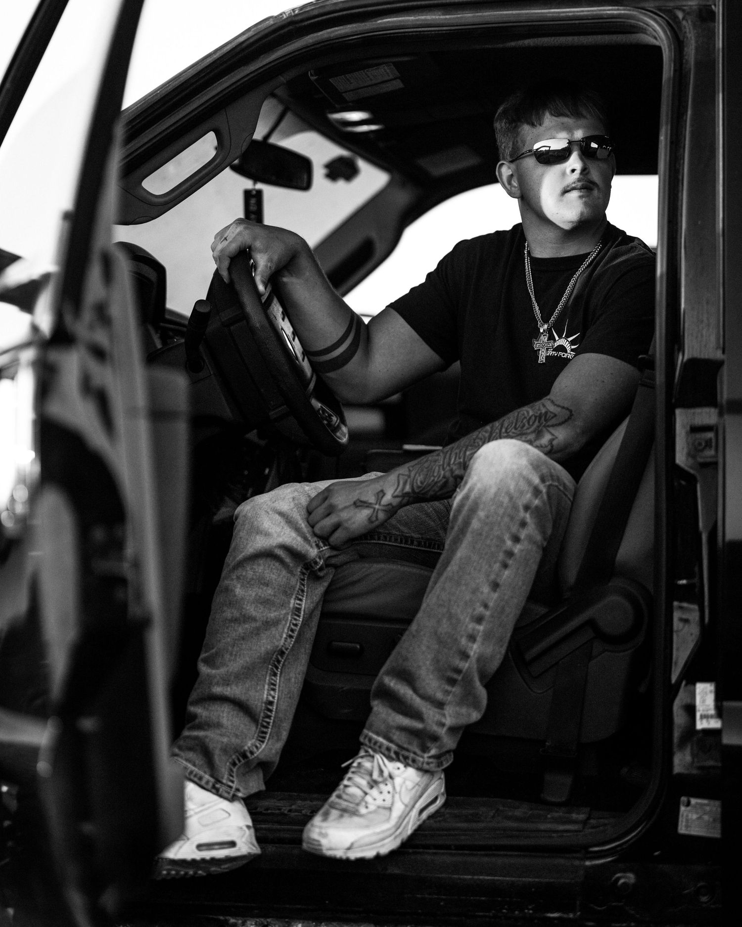 Person sitting in a car at night shown in black and white photography.
