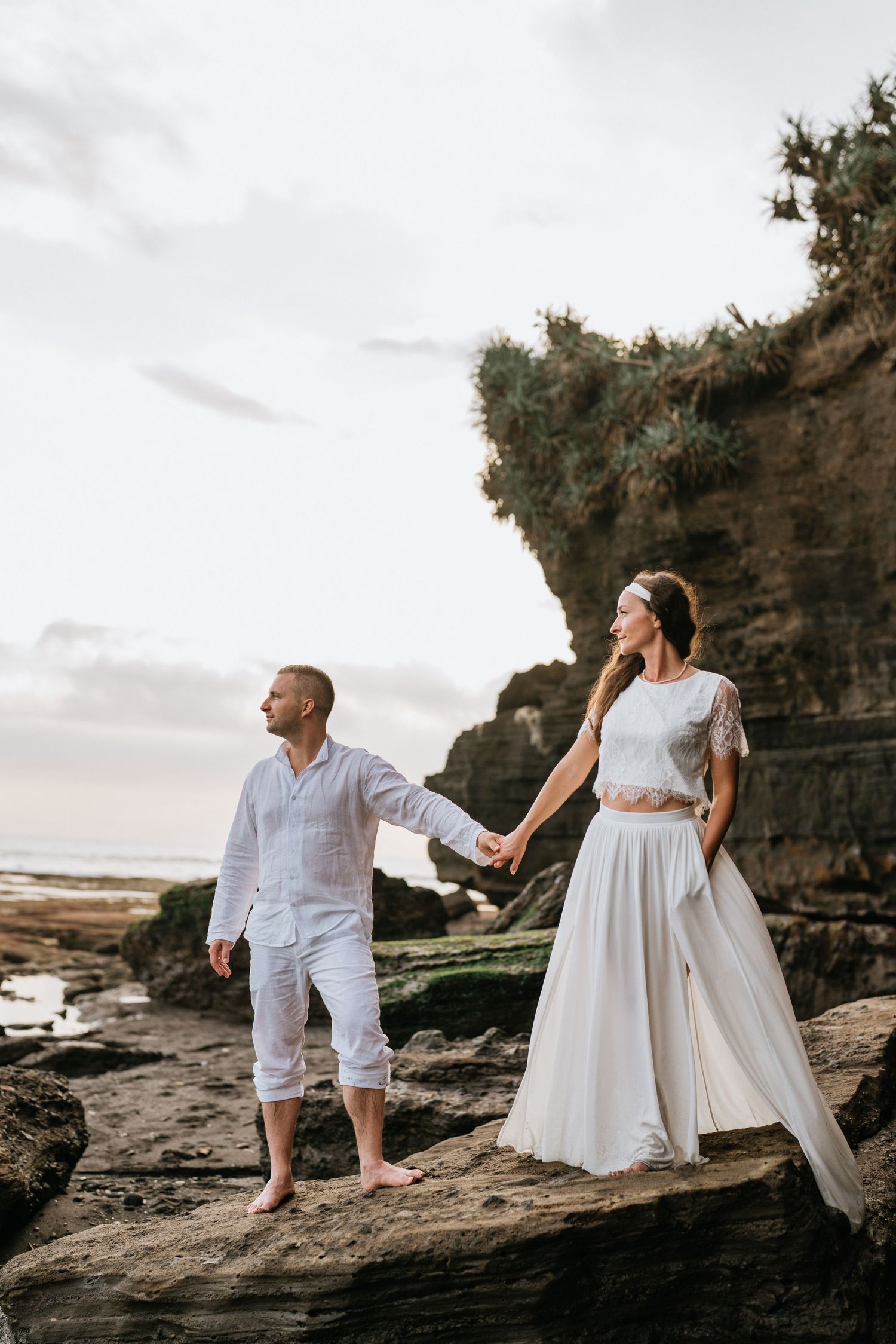 A romantic beach photoshoot with waves and cloudy skies in the background.
