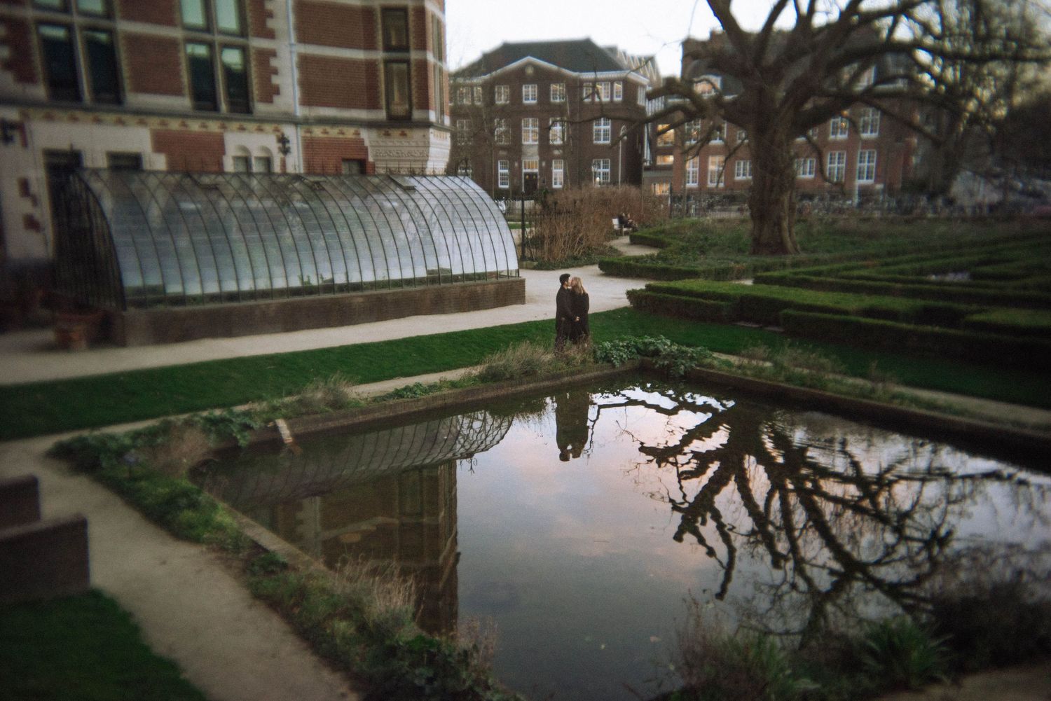 Panoramic view of ornate Victorian glasshouses in Rijkmuseum garden. Reflecting of the couple during love story photoshoot.