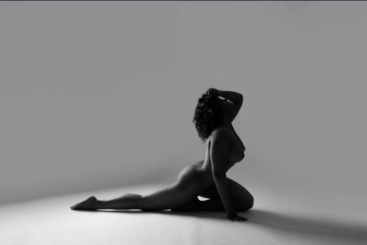 A dramatic black and white silhouette shows a ballet dancer in cobra pose against a minimalist background.
