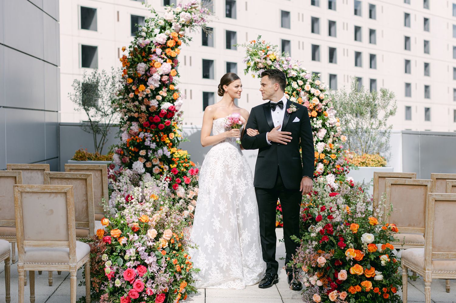 Modern building facade with colorful floral wedding decor and a couple in formal attire seen across multiple perspectives.